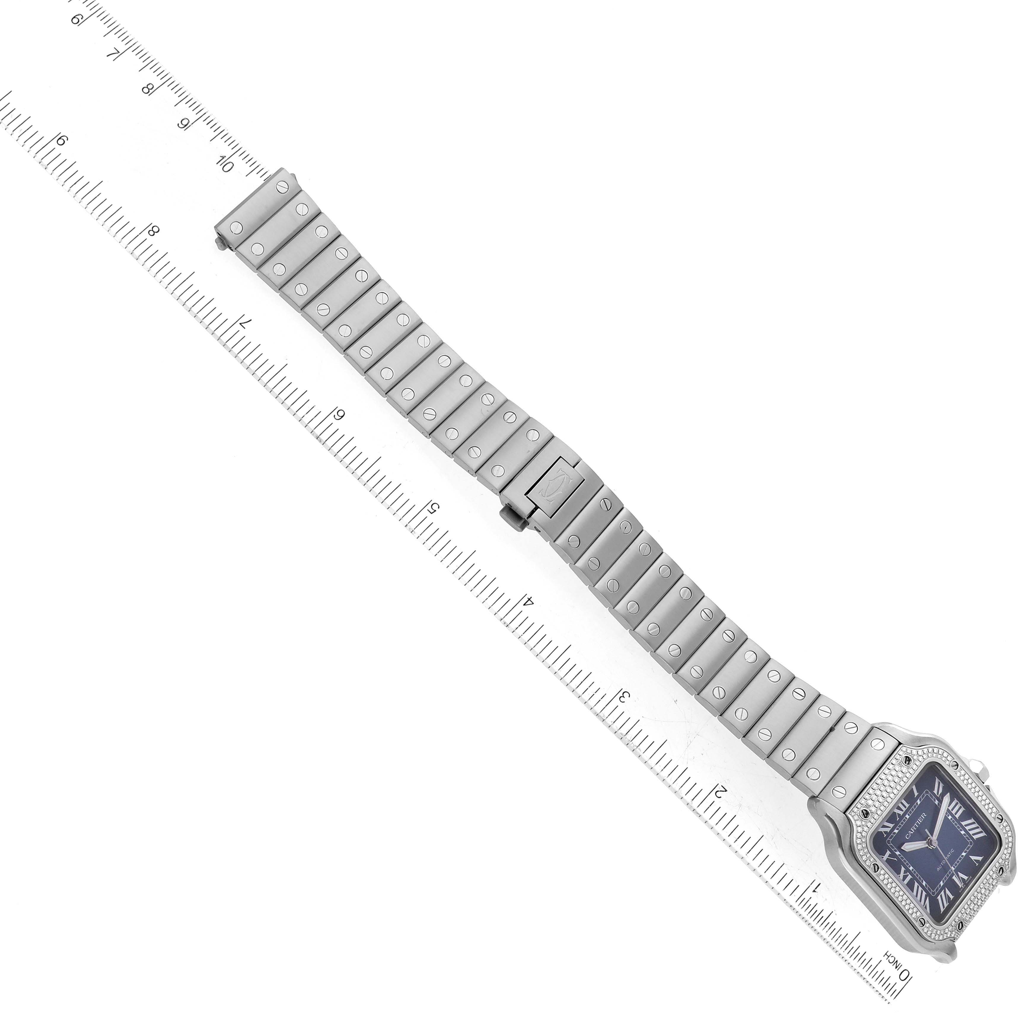 The image shows a Cartier Santos W4SA0006 Men's Stainless Steel Blue Dial W4SA0006 Men's Stainless Steel Blue Dial watch at a top-down angle, displaying the face, bezel, and full bracelet with a ruler for scale.