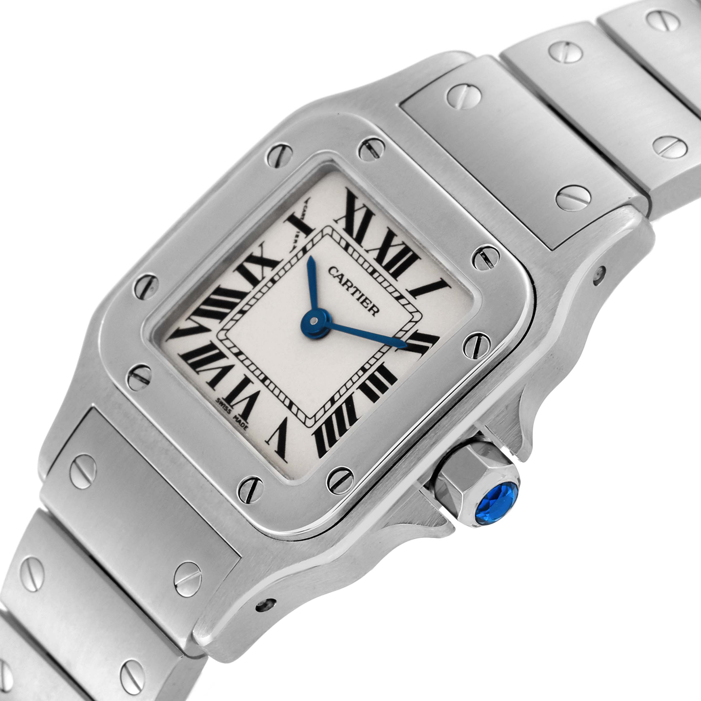 The image shows a close-up of the Cartier Santos W20056D6 Women's Stainless Steel Silver Dial W20056D6 Women's Stainless Steel Silver Dial watch face, bezel, blue-cabochon crown, and metal bracelet.