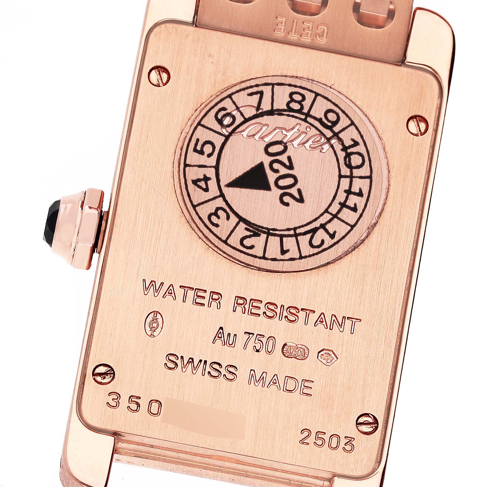 The image shows the back of a Cartier Tank Américaine watch, featuring its various engravings and stampings.