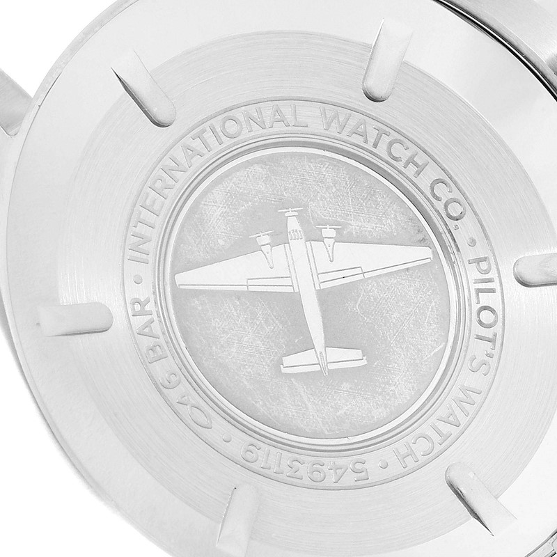 This image shows the case back of an IWC Pilot model watch, featuring an engraved airplane and brand inscriptions.