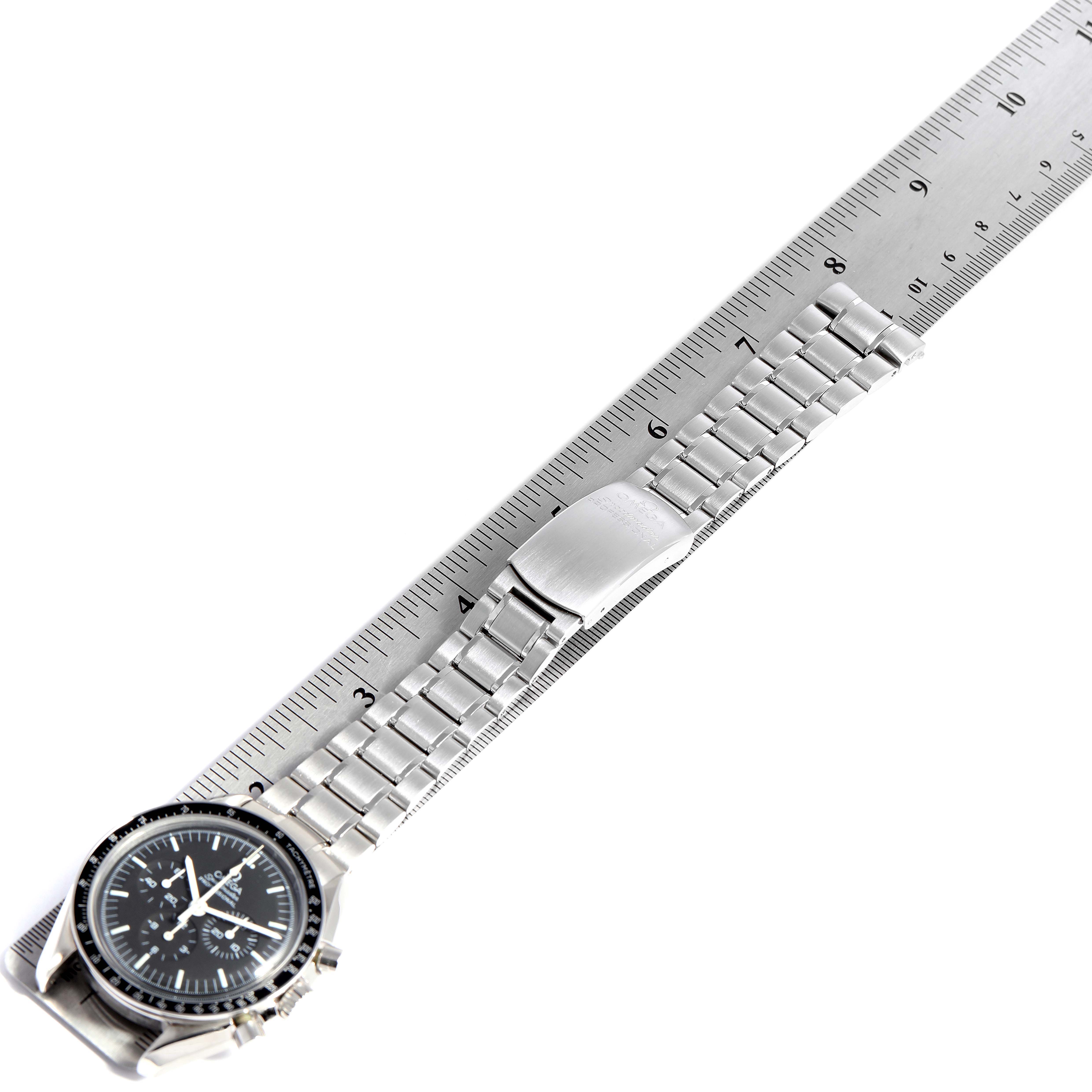 The Omega Speedmaster 3572.50.00 Men
s Stainless Steel Black Dial 3572.50.00 Men
s Stainless Steel Black Dial watch is shown from an overhead angle with its stainless steel bracelet aligned along a ruler.