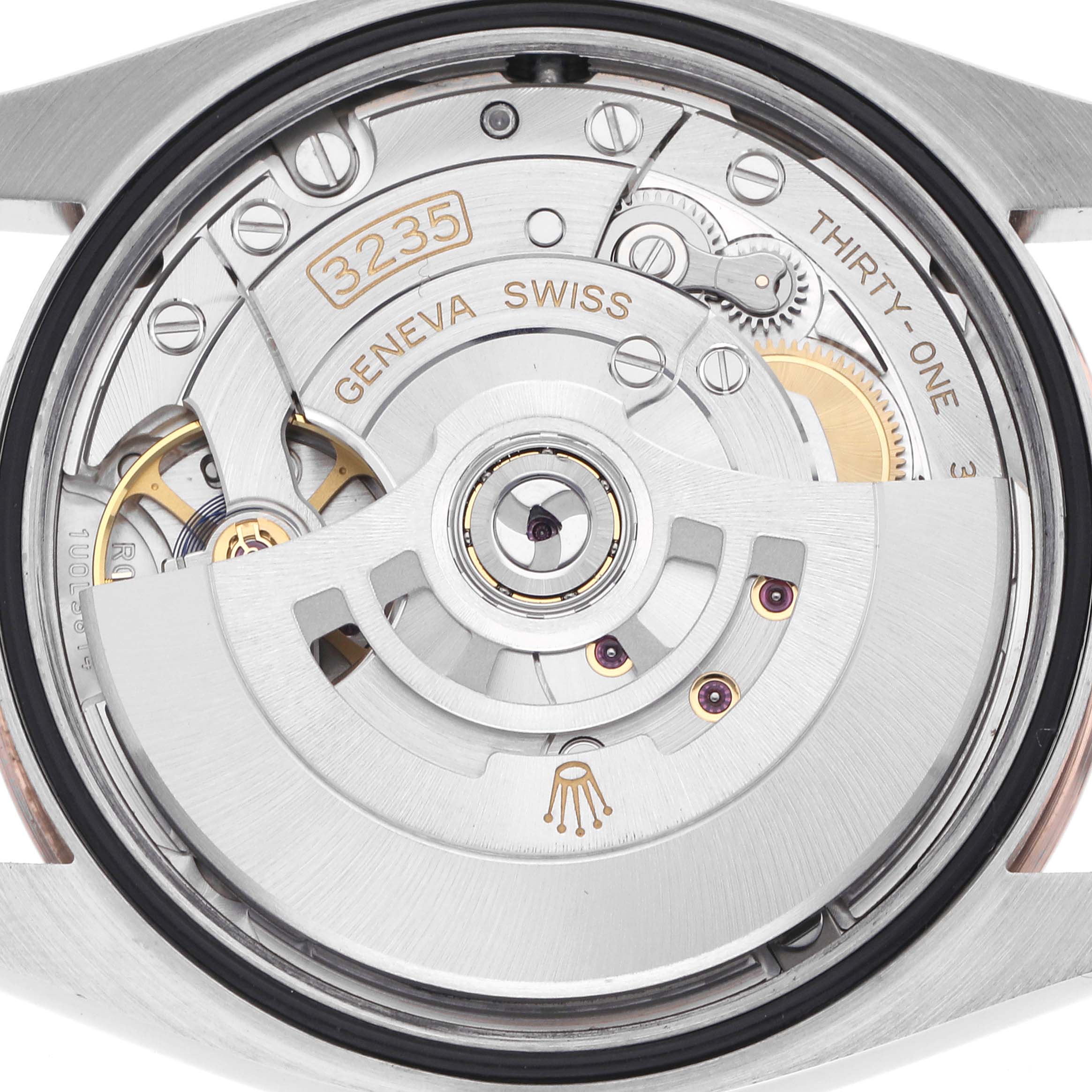 The image shows the movement of a Rolex Datejust 126201G Men's Steel and Gold (two tone) Brown Dial 126201G Men's Steel and Gold (two tone) Brown Dial, featuring the rotor and intricate gear components from the back angle.