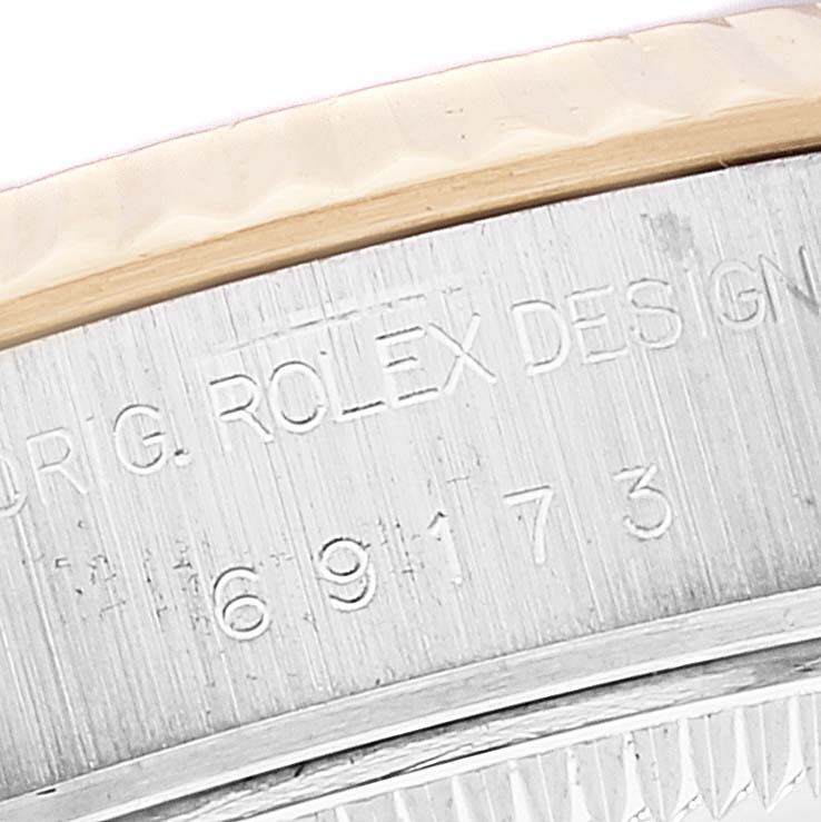 The image shows a close-up of the serial engraving on a Rolex Datejust 69173 Women's Steel and Gold (two tone) Blue Dial 69173 Women's Steel and Gold (two tone) Blue Dial's case and fluted bezel.