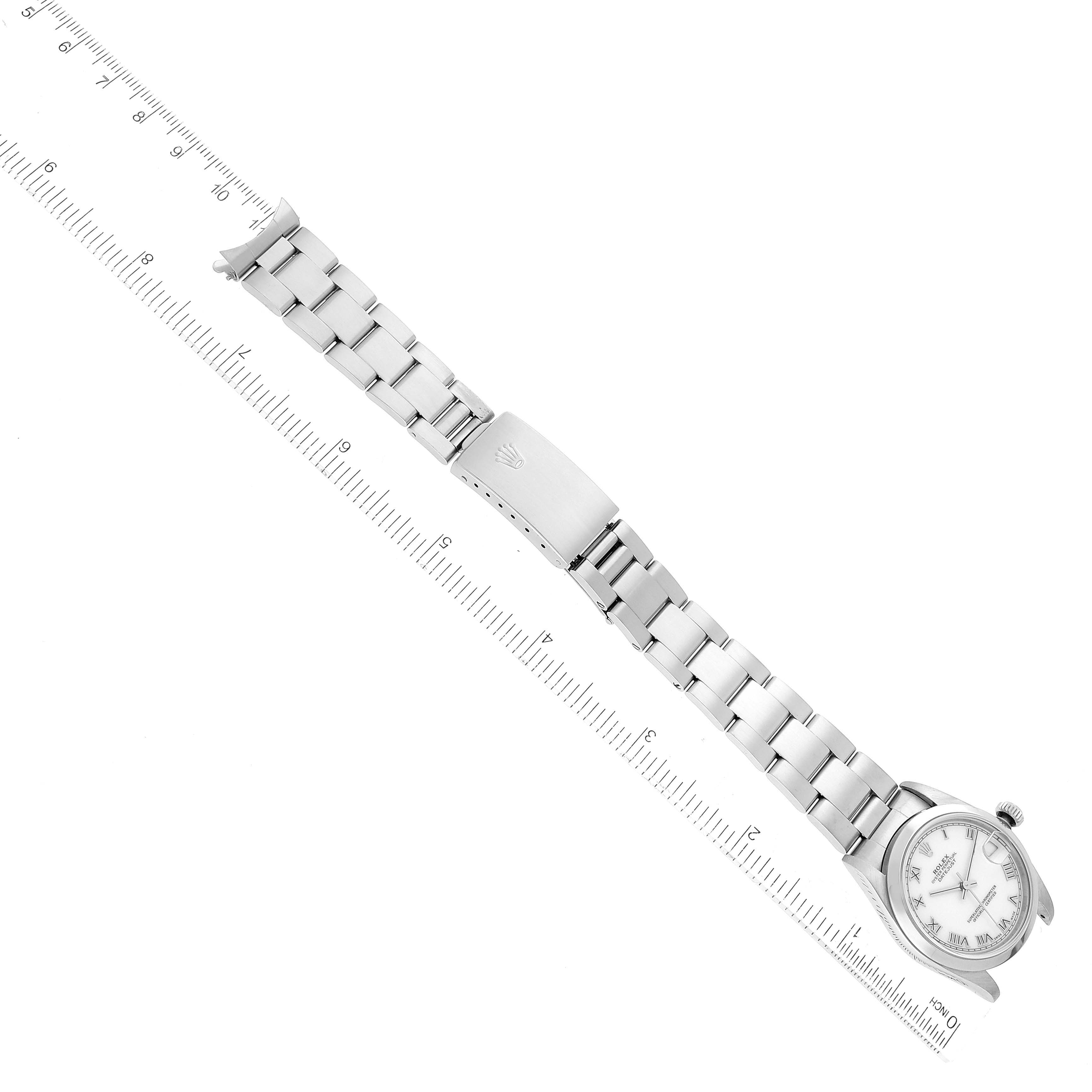 This image shows a Rolex Mid-Size 68240 Women
s Stainless Steel White Dial 68240 Women
s Stainless Steel White Dial model watch laid flat at a diagonal angle with its bracelet fully extended and a ruler for scale.