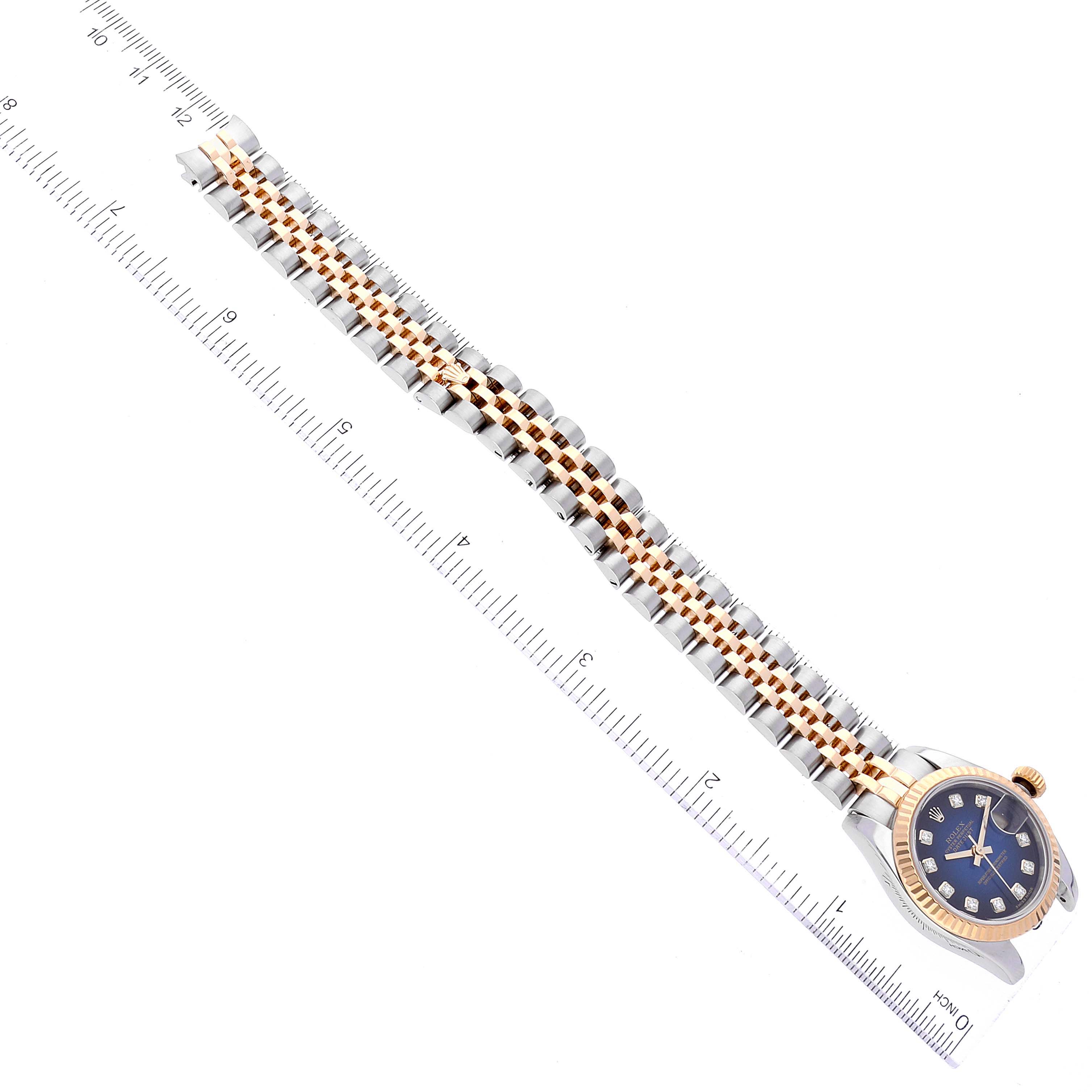 The image shows a Rolex Datejust 179173 Women's Steel and Gold (two tone) Blue Dial 179173 Women's Steel and Gold (two tone) Blue Dial watch laid flat with its bracelet fully extended alongside a ruler.
