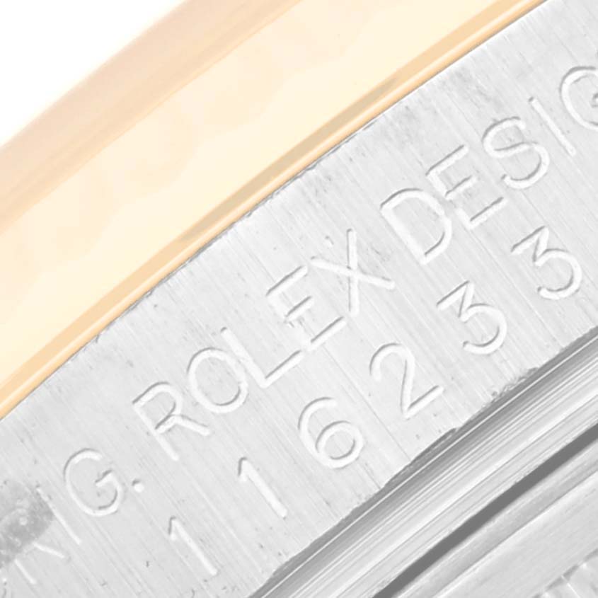 This image shows an extreme close-up of the side engraving on the bezel of a Rolex Datejust 116233 Men's Steel and Gold (two tone) Beige Dial 116233 Men's Steel and Gold (two tone) Beige Dial watch.