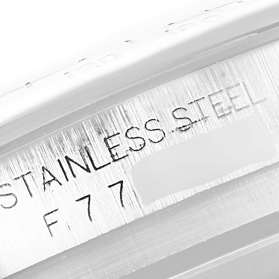 This image shows a close-up view of the Rolex Daytona 116520 Men
s Stainless Steel Black Dial 116520 Men
s Stainless Steel Black Dial watch, focusing on the "STAINLESS STEEL" engraving and partial serial number.