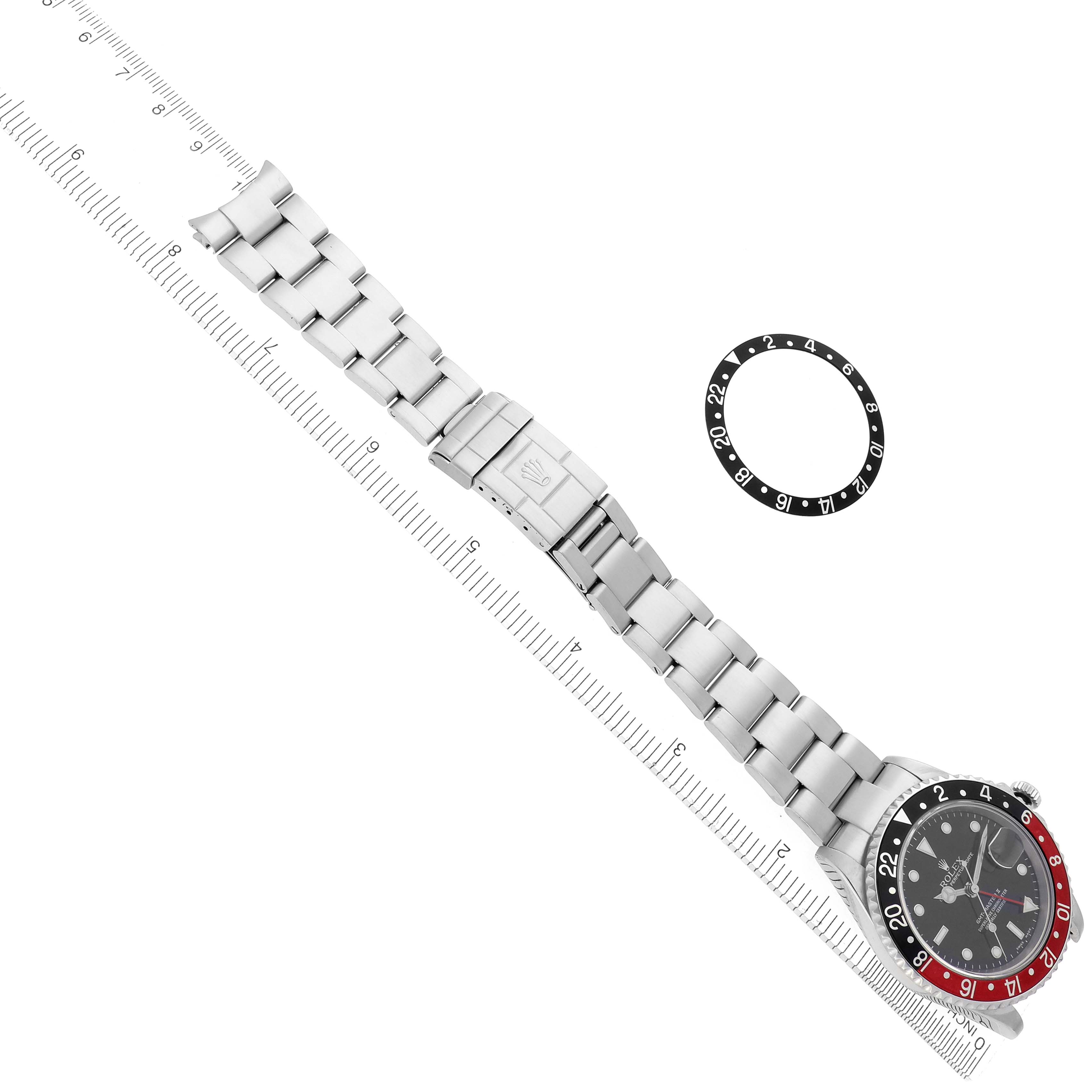 The image shows a Rolex GMT-Master 16710 Men's Stainless Steel Black Dial 16710 Men's Stainless Steel Black Dial watch and its bracelet at a diagonal angle with a bezel insert placed beside it.