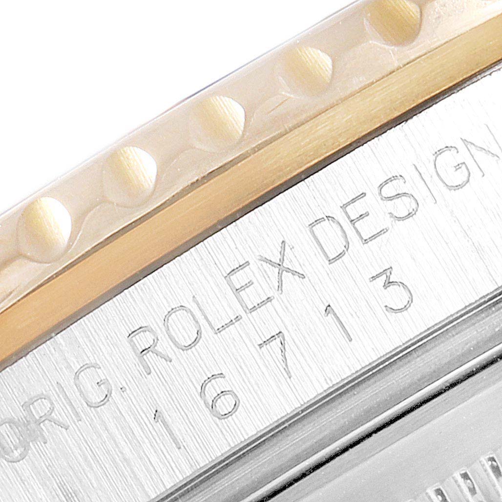 The image shows a close-up of the side engraving and bezel of a Rolex GMT-Master 16713 Men's Steel and Gold (two tone) Black Dial 16713 Men's Steel and Gold (two tone) Black Dial watch.