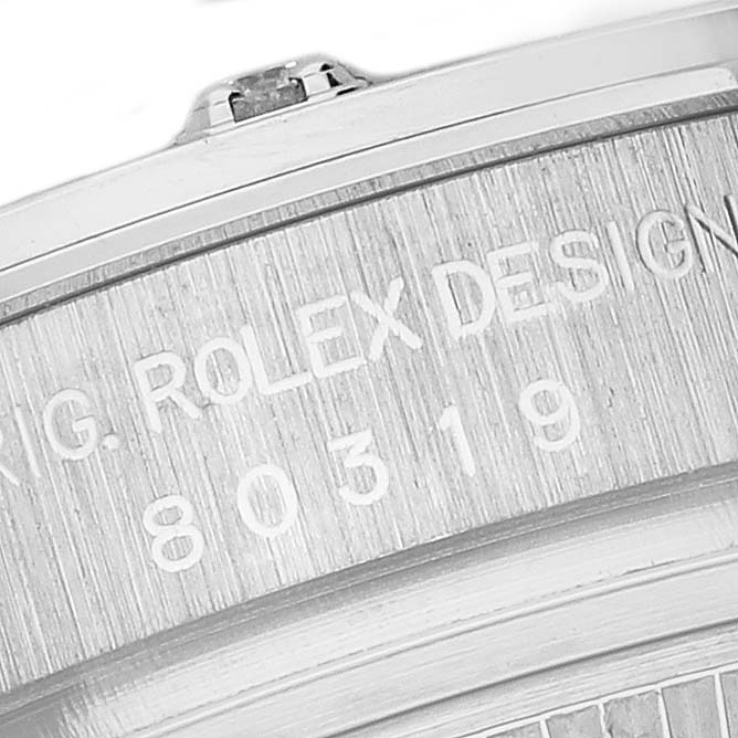 The image shows an angled close-up of the Rolex Pearlmaster 80319 Women
s White Gold Blue Dial 80319 Women
s White Gold Blue Dial’s engraved side with part of the bezel and crown.
