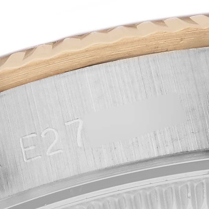 The image shows a close-up of the bezel and case side of a Rolex Oyster Perpetual 67193 Women's Steel and Gold (two tone) Champagne Dial 67193 Women's Steel and Gold (two tone) Champagne Dial watch, featuring part of its engraved serial number.