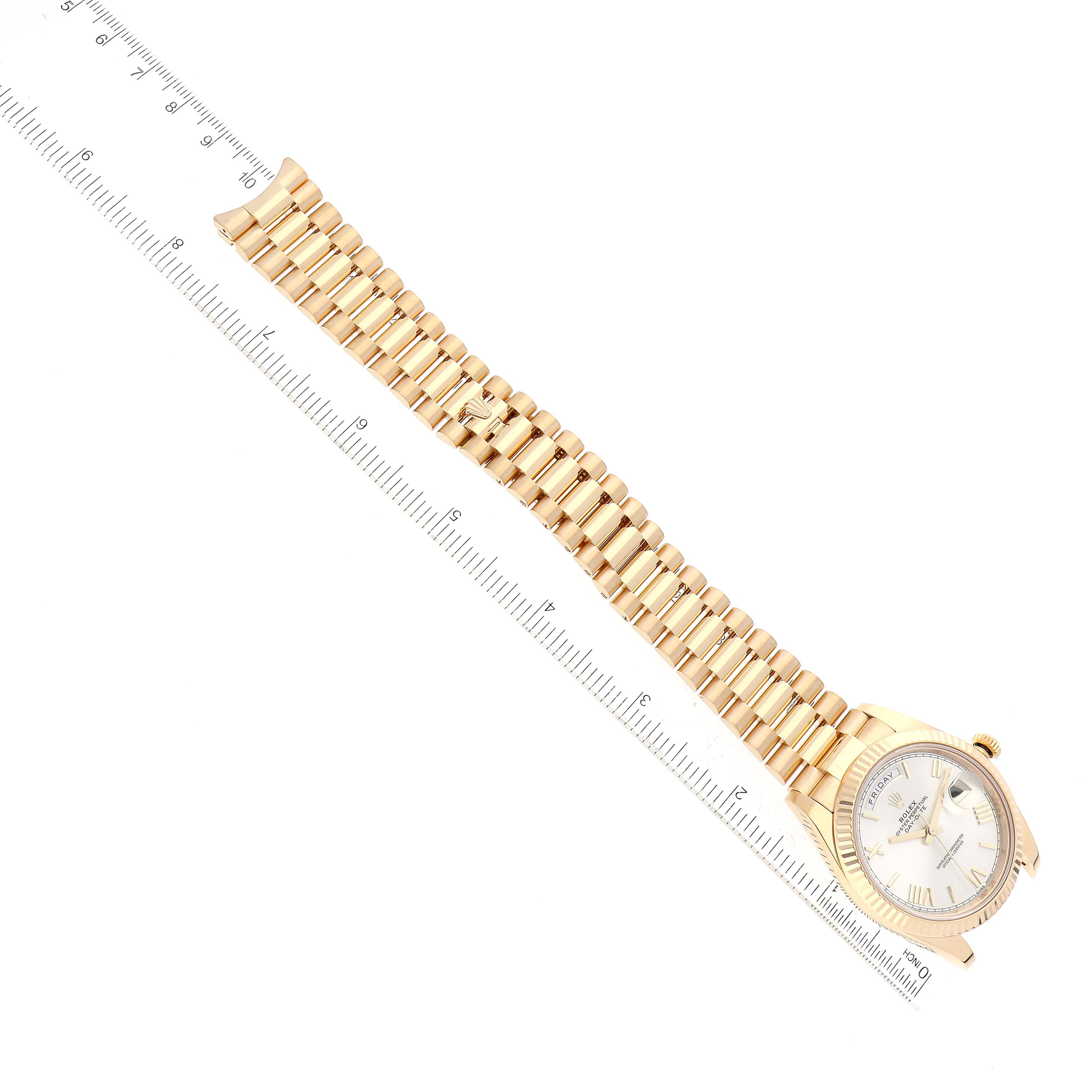 The image shows a top view of a Rolex President 228238 Men
s Yellow Gold Silver Dial 228238 Men
s Yellow Gold Silver Dial model watch with its full band extended alongside a ruler for measurement.