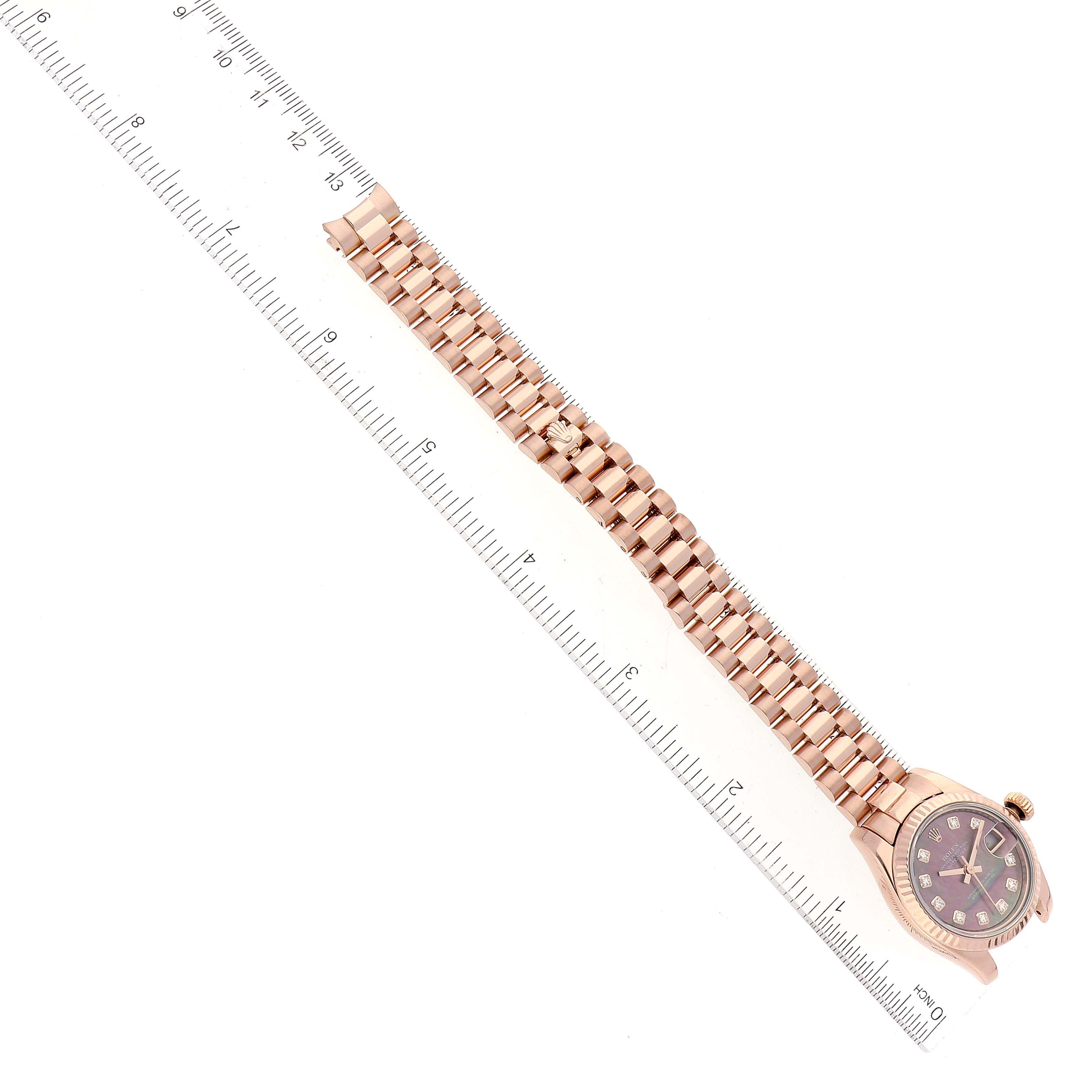 This image shows a side view of a Rolex President 179175 Women's Rose Gold Mother of Pearl Dial 179175 Women's Rose Gold Mother of Pearl Dial model watch alongside a ruler for size reference.