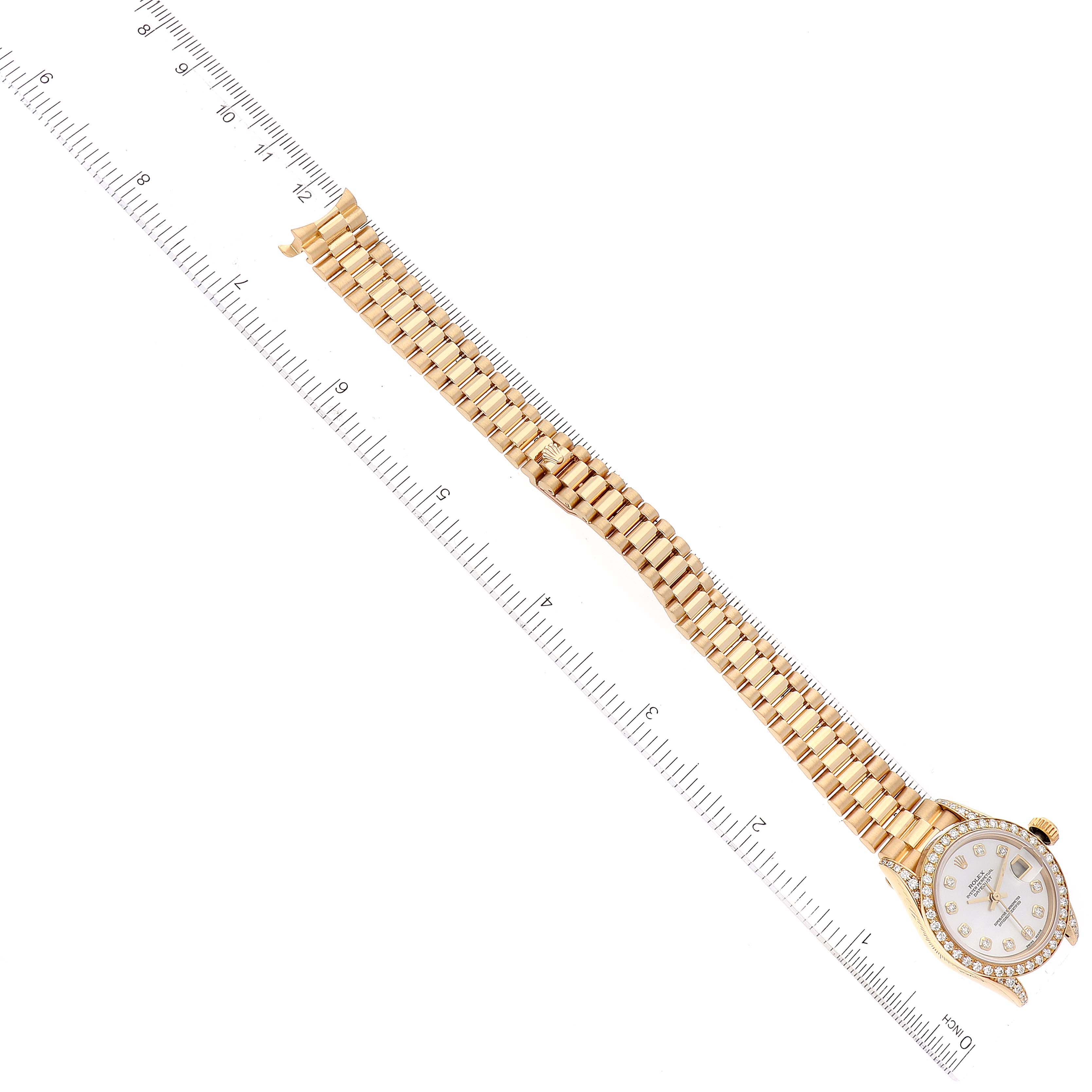 The image shows a Rolex President 69158 Women's Yellow Gold Mother of Pearl Dial 69158 Women's Yellow Gold Mother of Pearl Dial model watch laid flat next to a ruler, showcasing its full length and detailed bracelet.