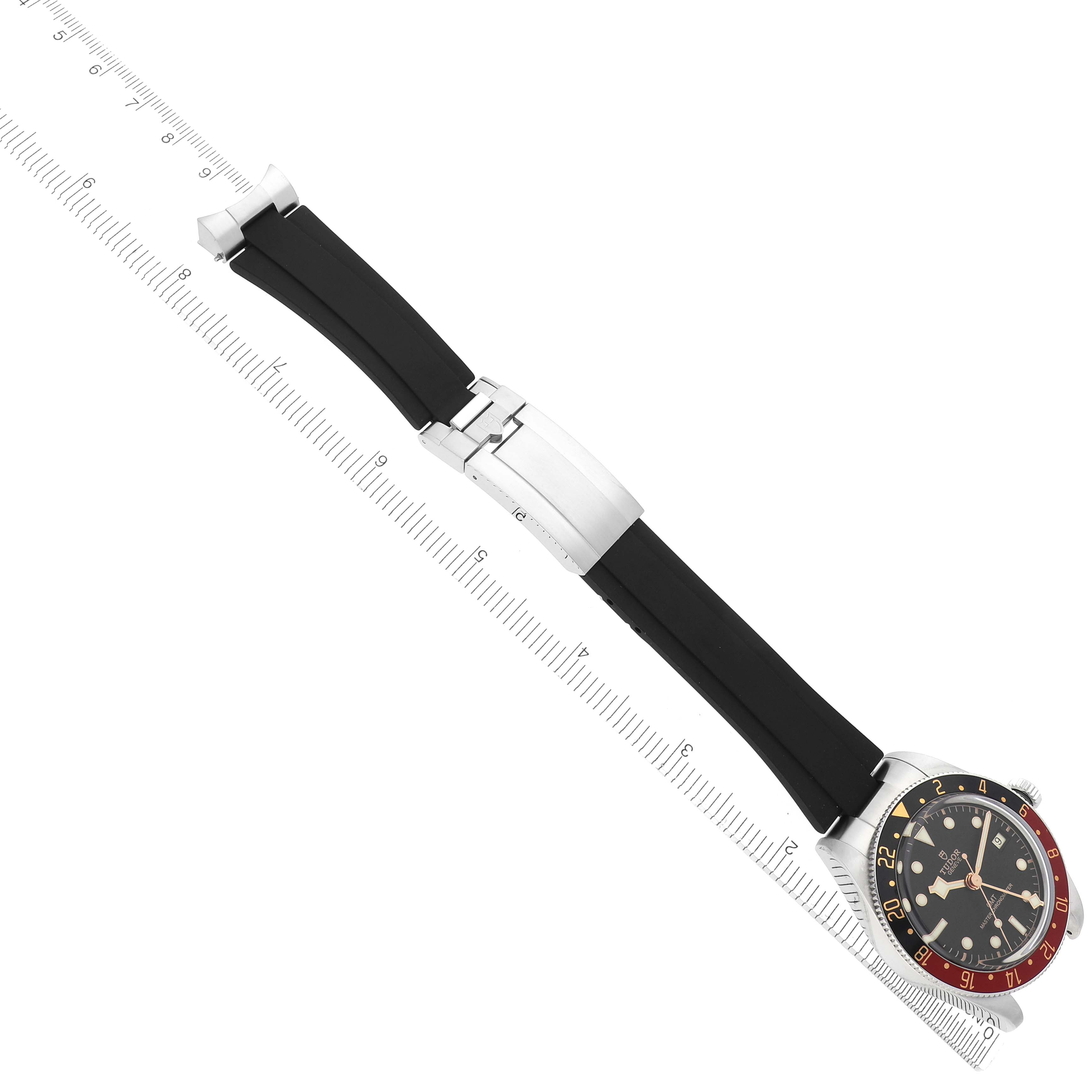 The Tudor Heritage Black Bay M7939G1A0NRU-0002 Men
s Stainless Steel Black Dial M7939G1A0NRU-0002 Men
s Stainless Steel Black Dial watch is shown from above, featuring the face, case, and black strap with a ruler alongside it.