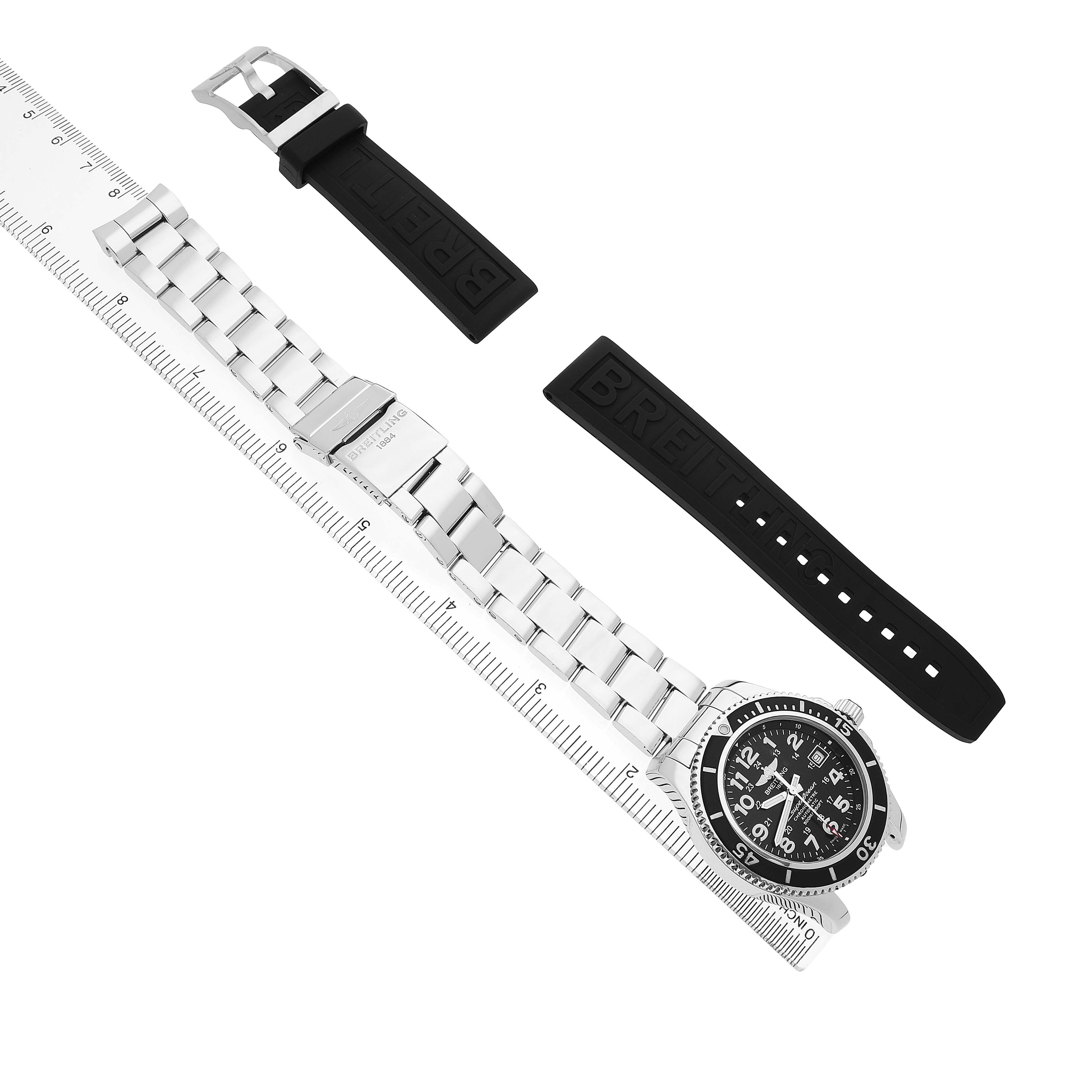 The Breitling Superocean A17365 Men's Stainless Steel Black Dial watch is shown from above, featuring a metal bracelet, clasp, and two rubber strap options alongside a ruler.