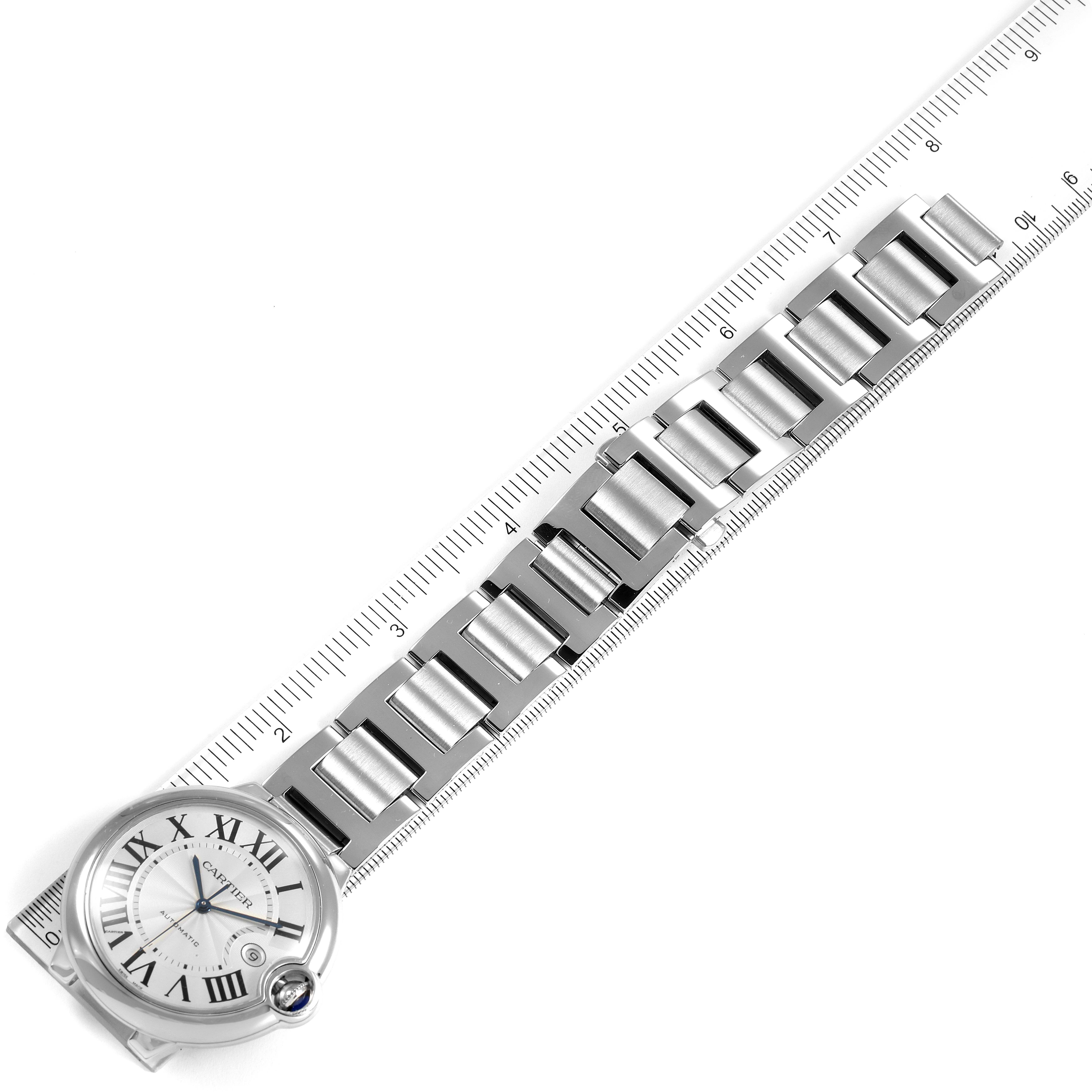The image shows a top-down view of a Cartier Ballon Bleu W69012Z4 Men's Stainless Steel Silver Dial W69012Z4 Men's Stainless Steel Silver Dial watch with its face and linked metal bracelet alongside a ruler.