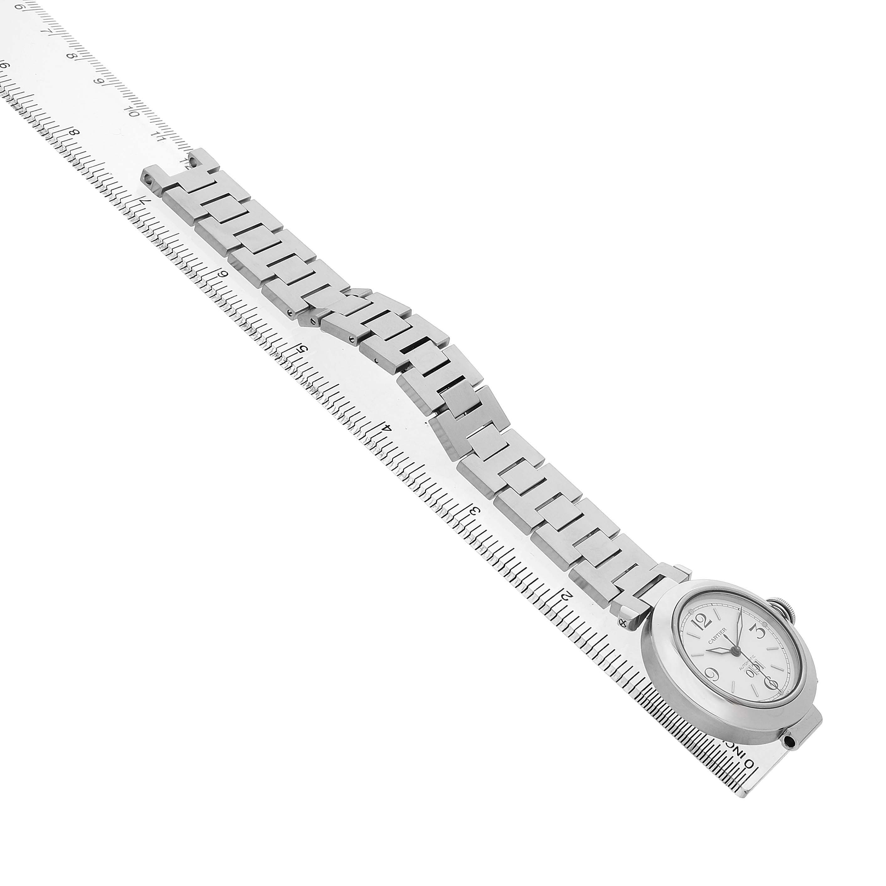 The Cartier Pasha W31044M7 Men's Stainless Steel White Dial watch is shown from a side angle, highlighting the bracelet and face alongside a measuring ruler.