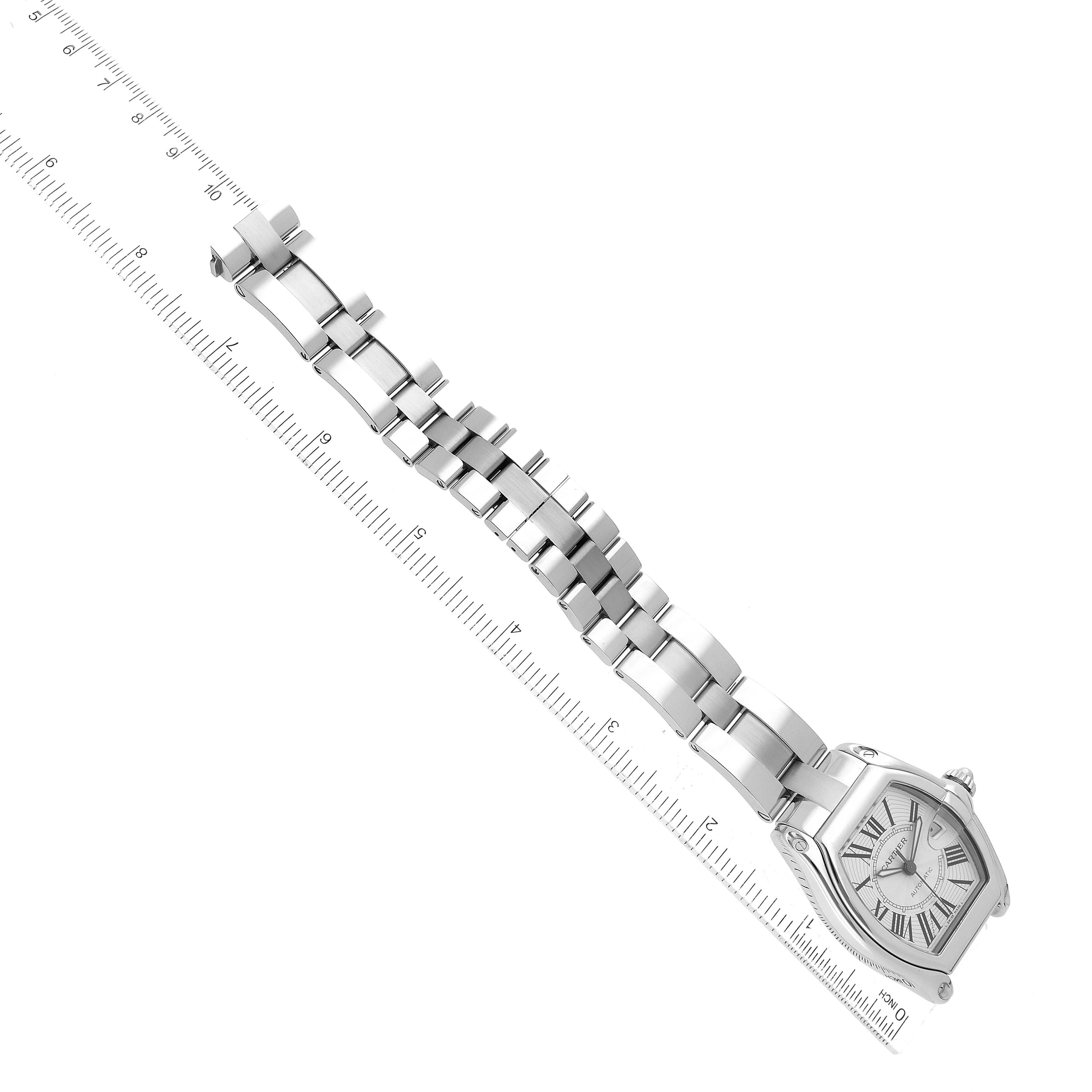 The image shows a side angle of a Cartier Roadster W62025V3 Men's Stainless Steel Silver Dial W62025V3 Men's Stainless Steel Silver Dial watch with a metal bracelet next to a ruler.