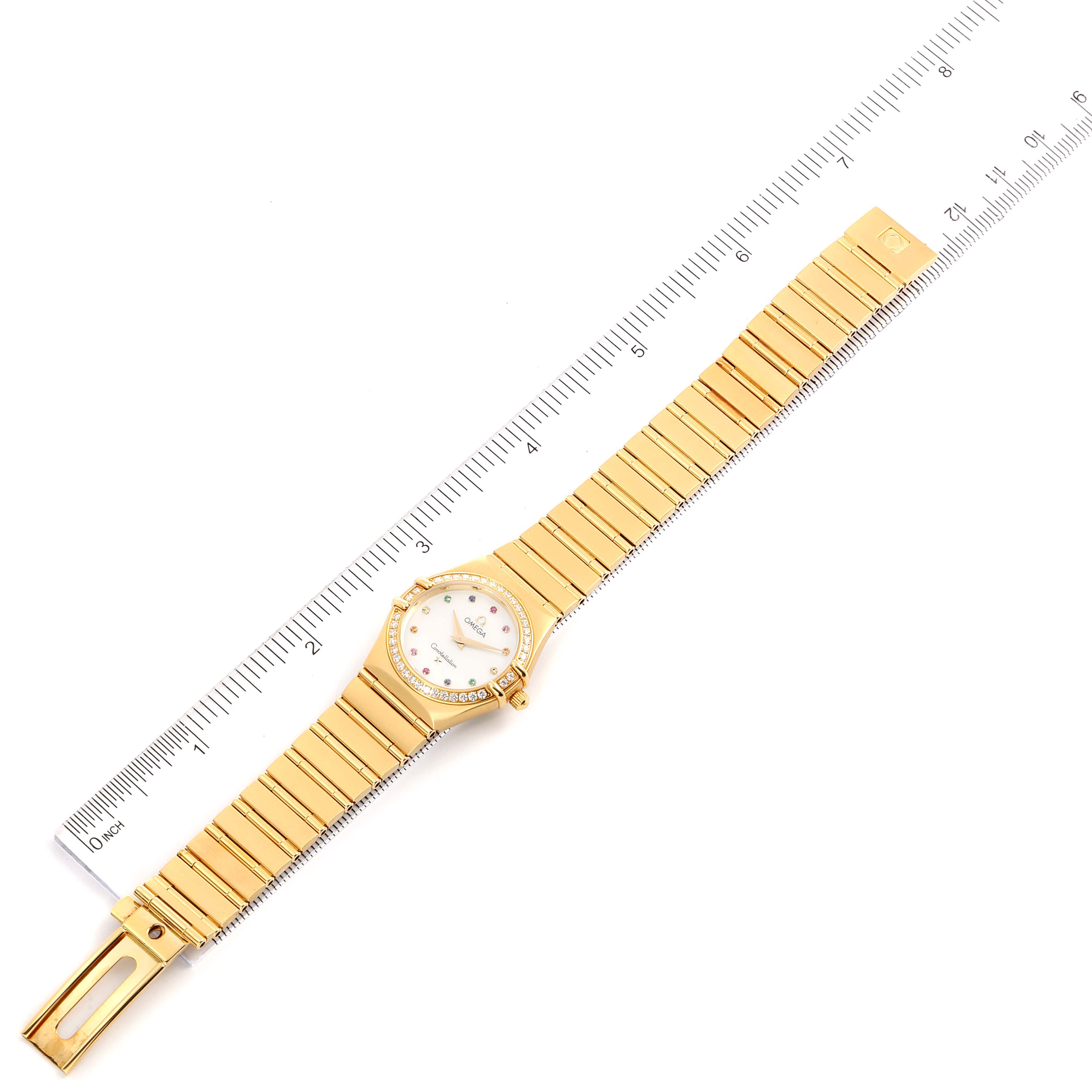 The image shows the Omega 1177.79.00 Women's White Gold Mother of Pearl Dial 1177.79.00 Women's White Gold Mother of Pearl Dial Constellation Iris Yellow Gold Multi Stone Watch 1177.79.00 laid flat with a ruler for scale.