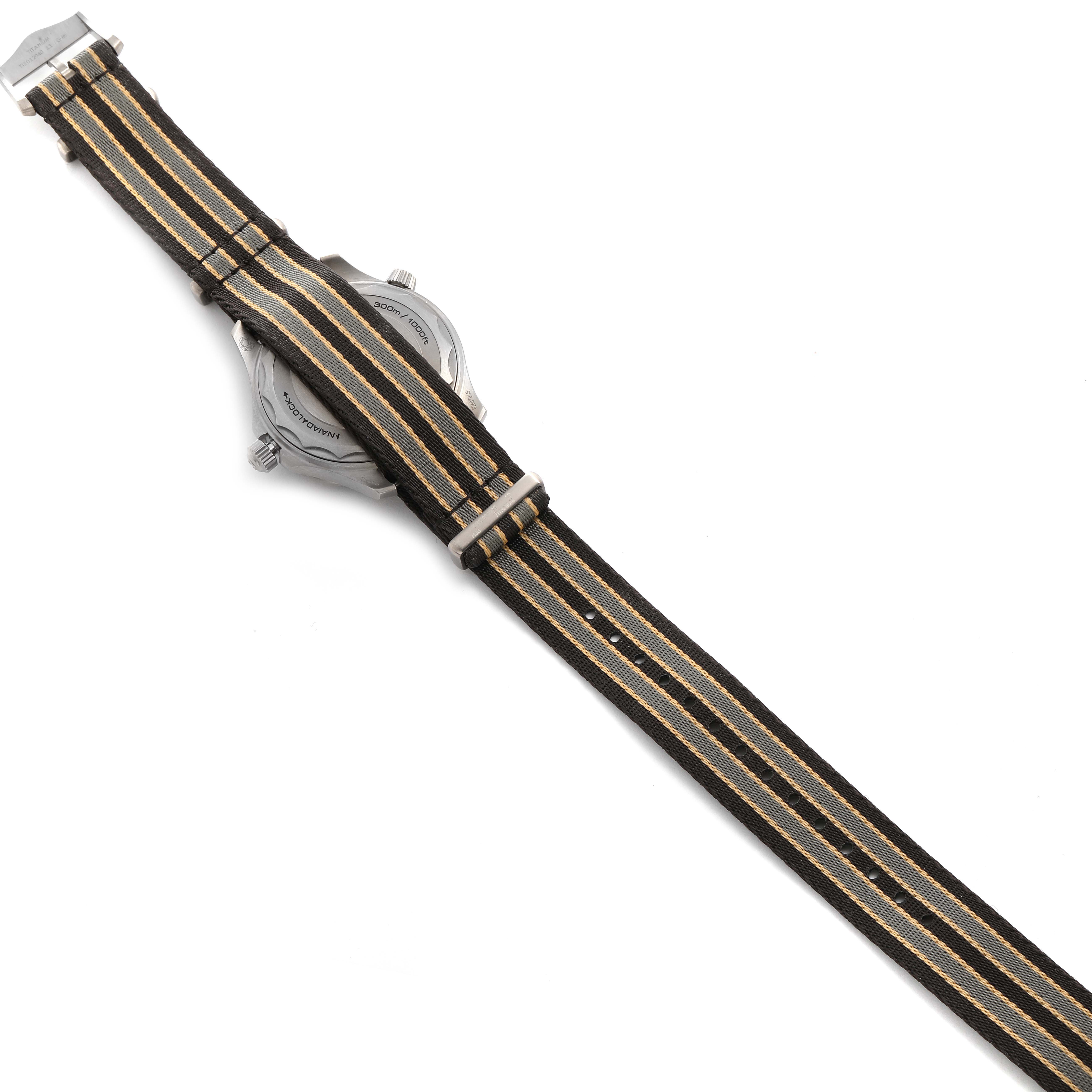 The image shows the back of an Omega Seamaster 210.92.42.20.01.001 Men's Titanium Brown Dial 210.92.42.20.01.001 Men's Titanium Brown Dial watch and its striped fabric strap.