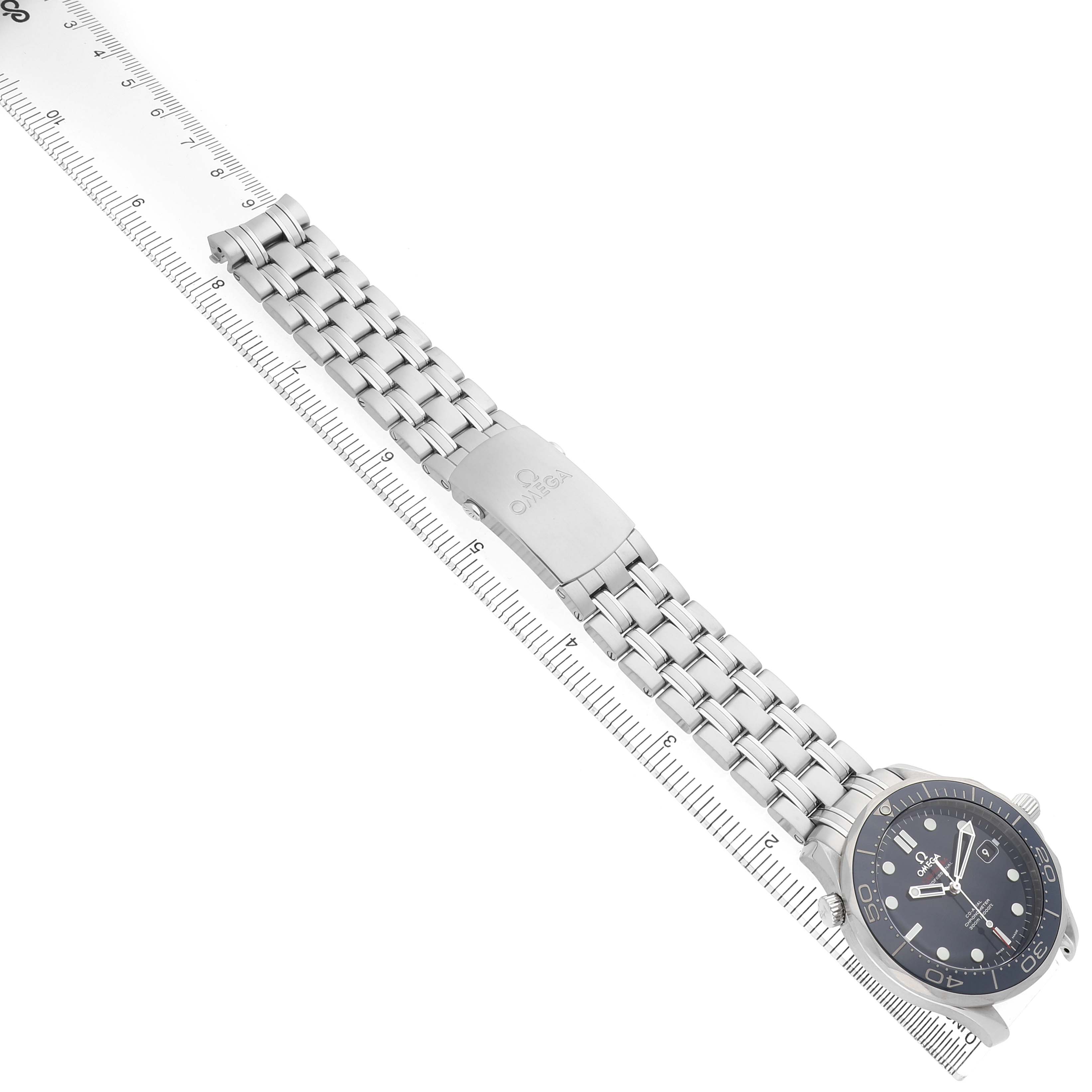 The Omega Seamaster 212.30.41.20.03.001 Men's Stainless Steel Blue Dial watch is shown at a top-down angle, highlighting the bracelet, clasp, and face next to a ruler.