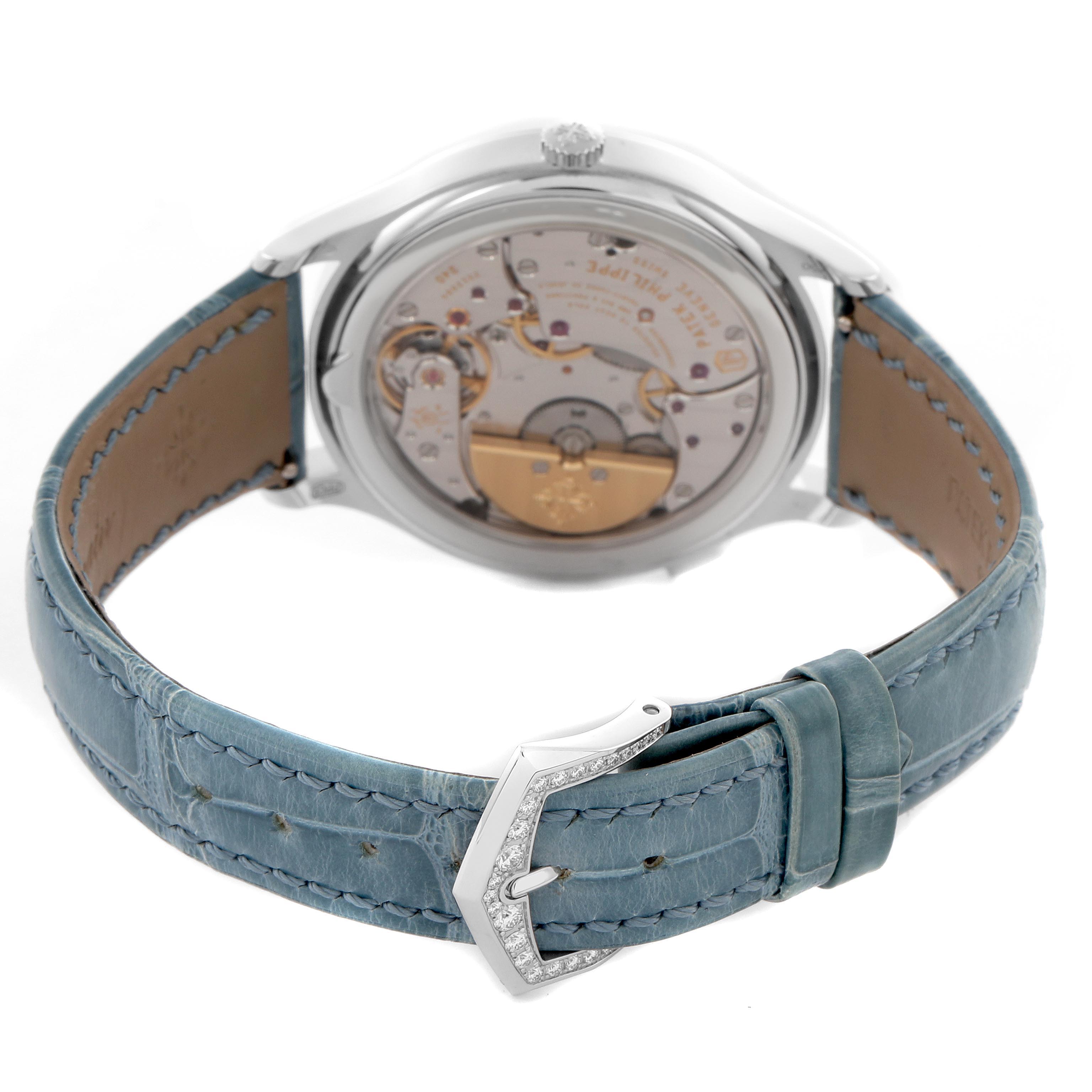 The Patek Philippe Complications 7130G-016 Men
s White Gold Blue Dial 7130G-016 Men
s White Gold Blue Dial watch is viewed from the back, showcasing its movement and the blue leather strap with an ornate buckle.