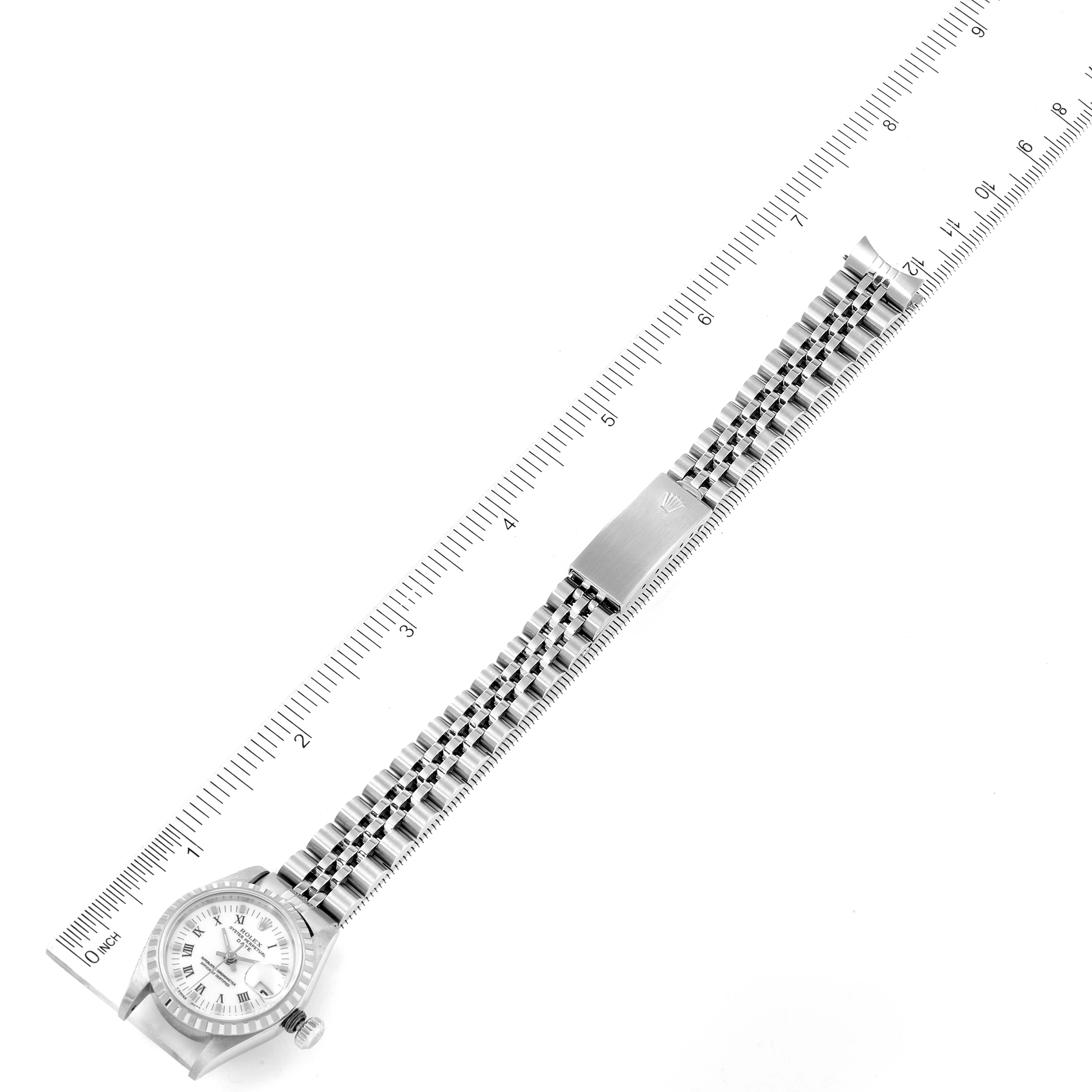 The image shows a top-down view of a Rolex Date 69240 Women's Stainless Steel White Dial 69240 Women's Stainless Steel White Dial model watch, displaying its face and metal bracelet laid alongside a ruler.