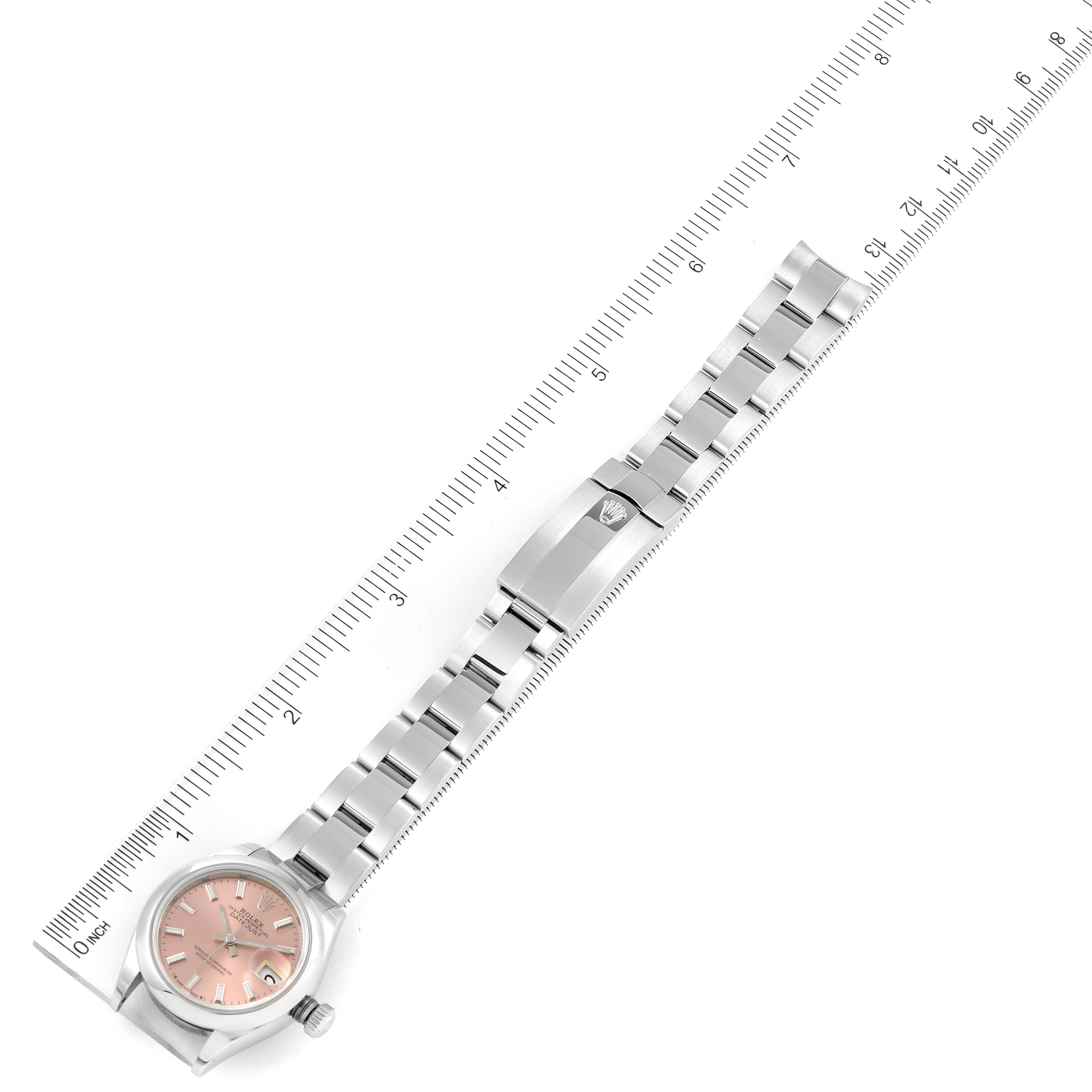 The Rolex Datejust 279160 Women's Stainless Steel Pink Dial 279160 Women's Stainless Steel Pink Dial watch is shown from an overhead angle, including the full bracelet, clasp, and the watch face with a ruler for scale.