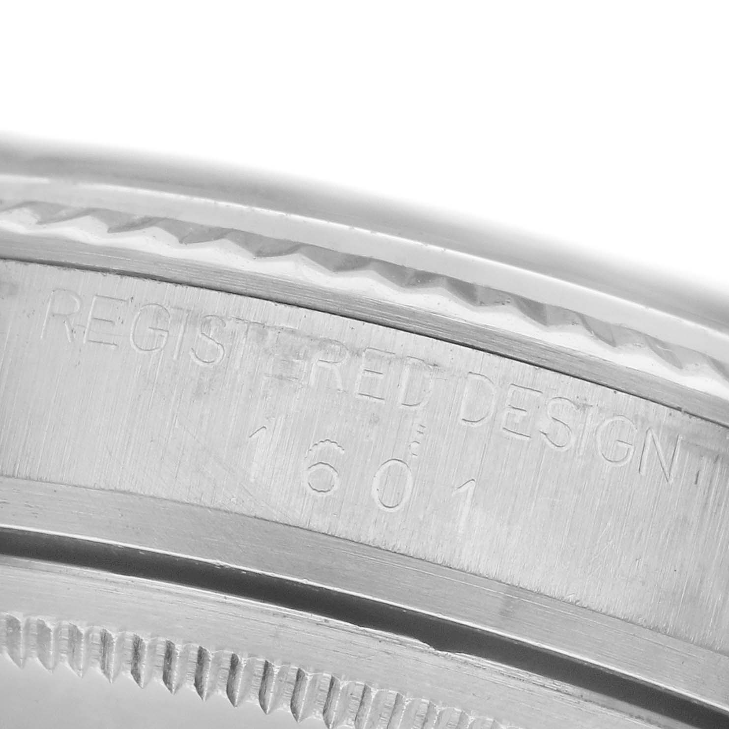 The image shows a close-up of the side of a Rolex Datejust 1601 Men
s Stainless Steel Blue Dial 1601 Men
s Stainless Steel Blue Dial, featuring engraved details and part of the bezel.