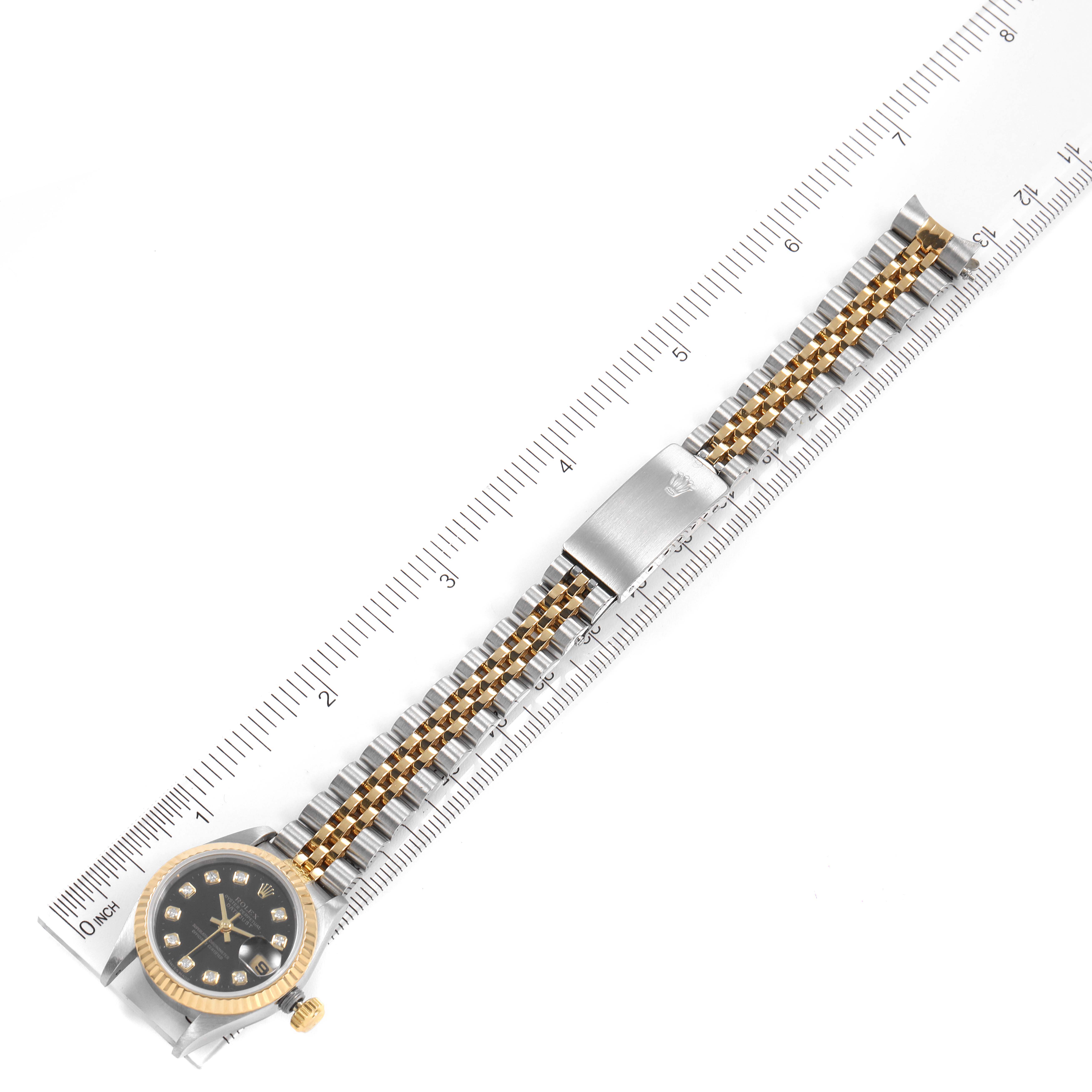 The image shows a top-down view of the Rolex Datejust 69173 Women's Steel and Gold (two tone) Black Dial 69173 Women's Steel and Gold (two tone) Black Dial watch, including its face, bezel, crown, and bracelet, placed next to a ruler.