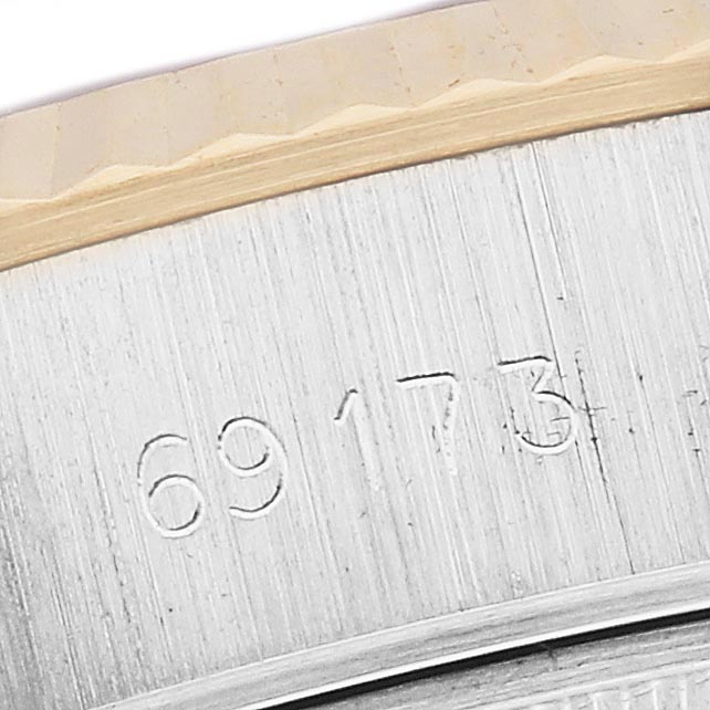 The image shows a close-up of a Rolex Datejust 69173 Women
s Steel and Gold (two tone) Silver Dial 69173 Women
s Steel and Gold (two tone) Silver Dial, specifically focusing on the engraved model number and the fluted bezel edge.
