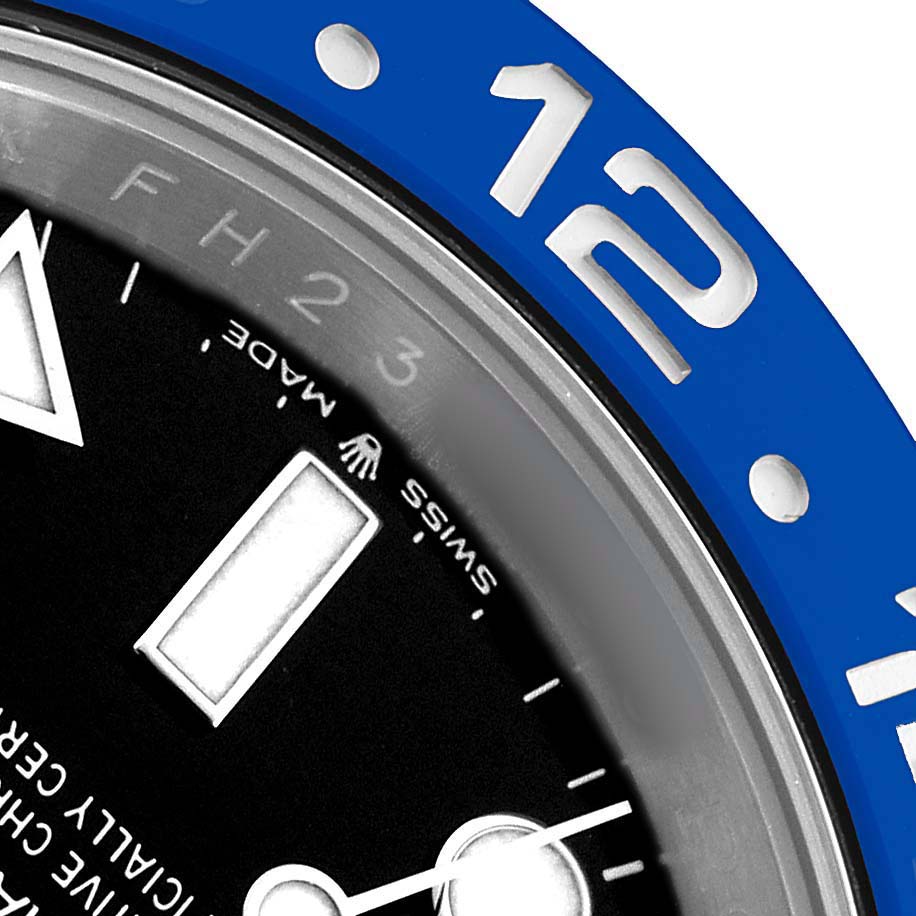 The image shows a close-up of the bezel and dial of a Rolex GMT-Master 126710BLNR Men's Stainless Steel Black Dial, focusing on the "12" marker and part of the hands.