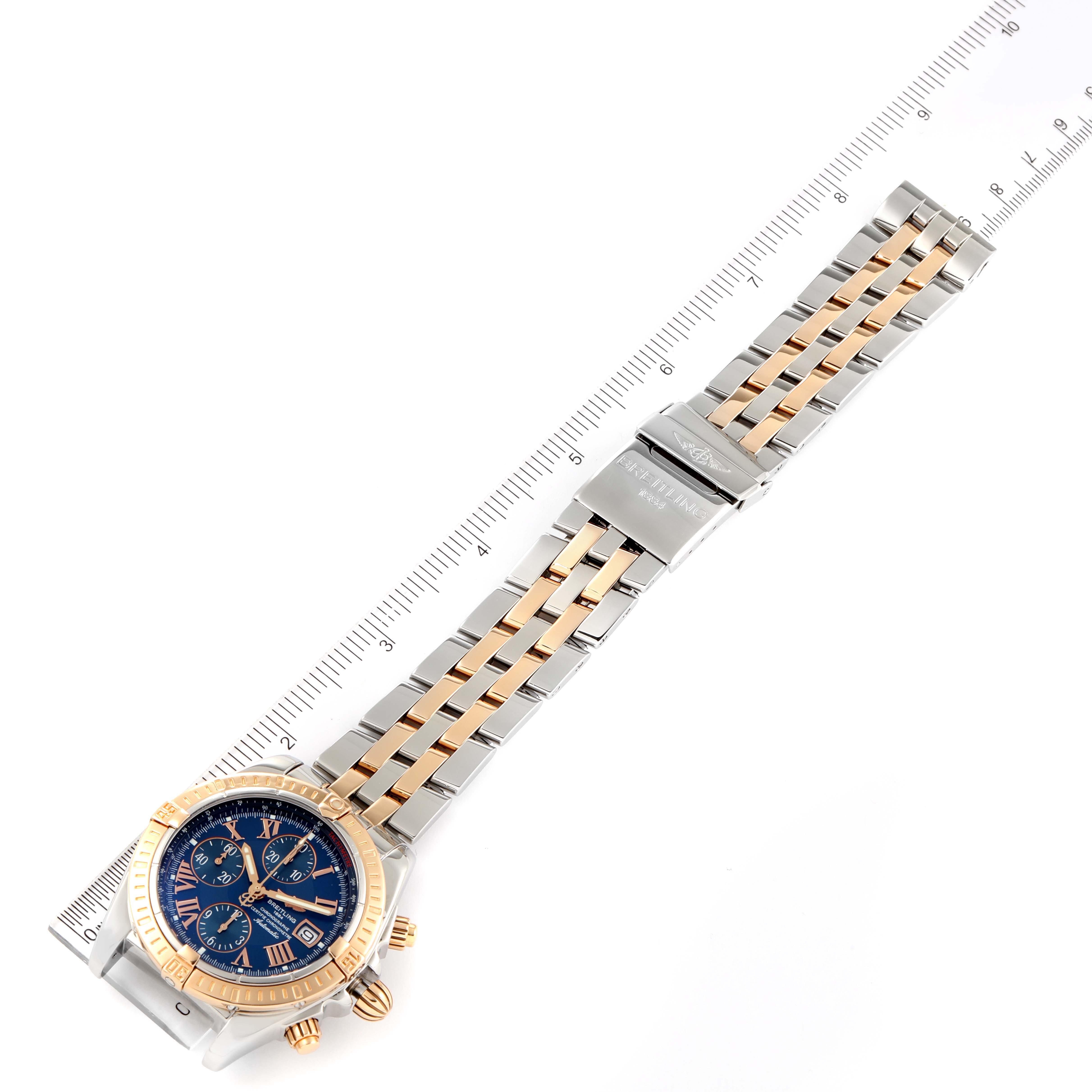 The image shows an overhead view of the Breitling Chronomat C13356 Men
s Steel and Gold (two tone) Blue Dial C13356 Men
s Steel and Gold (two tone) Blue Dial watch, highlighting the face and metal bracelet with a measuring ruler beside it.