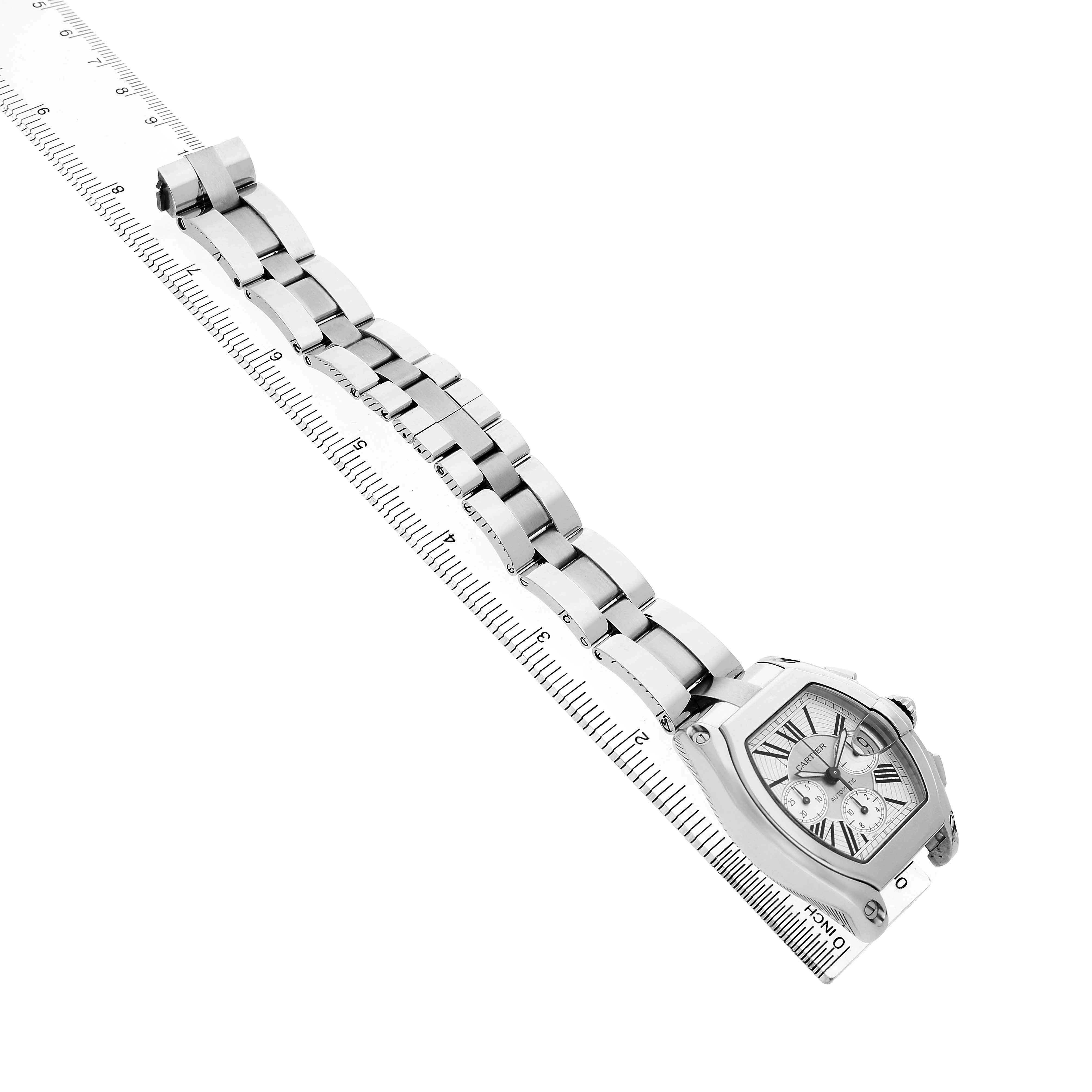 The Cartier Roadster W62019X6 Men's Stainless Steel Silver Dial watch is shown diagonally, highlighting the face, bracelet, and a ruler for scale.