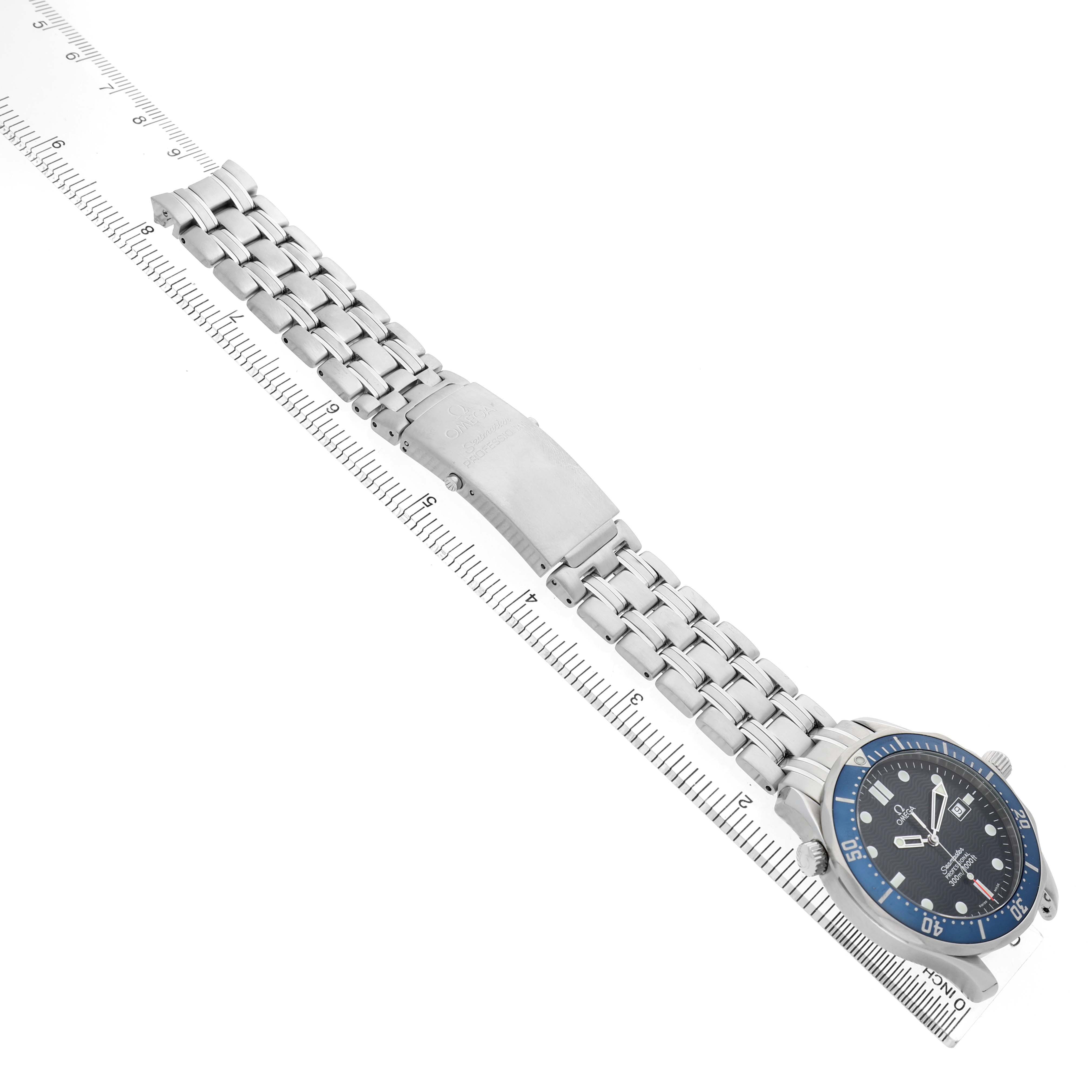 The Omega Seamaster 2541.80.00 Men's Stainless Steel Blue Dial watch is shown at an angle displaying its face, bracelet, and clasp, parallel to a ruler.