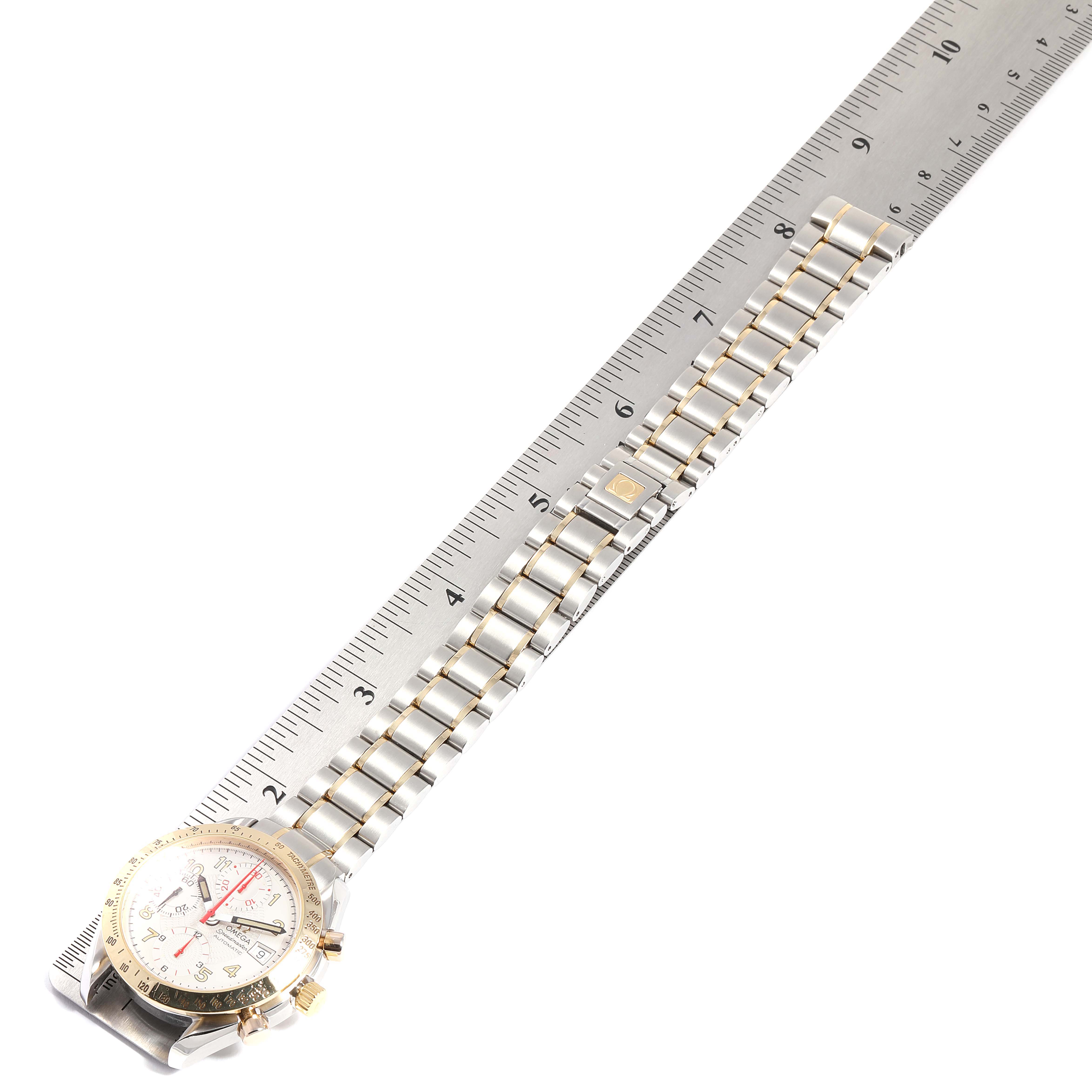 The image shows an Omega Speedmaster 3313.33.00 Men's Steel and Gold (two tone) White Dial 3313.33.00 Men's Steel and Gold (two tone) White Dial watch laid flat with a ruler beside it, displaying the face and full bracelet.