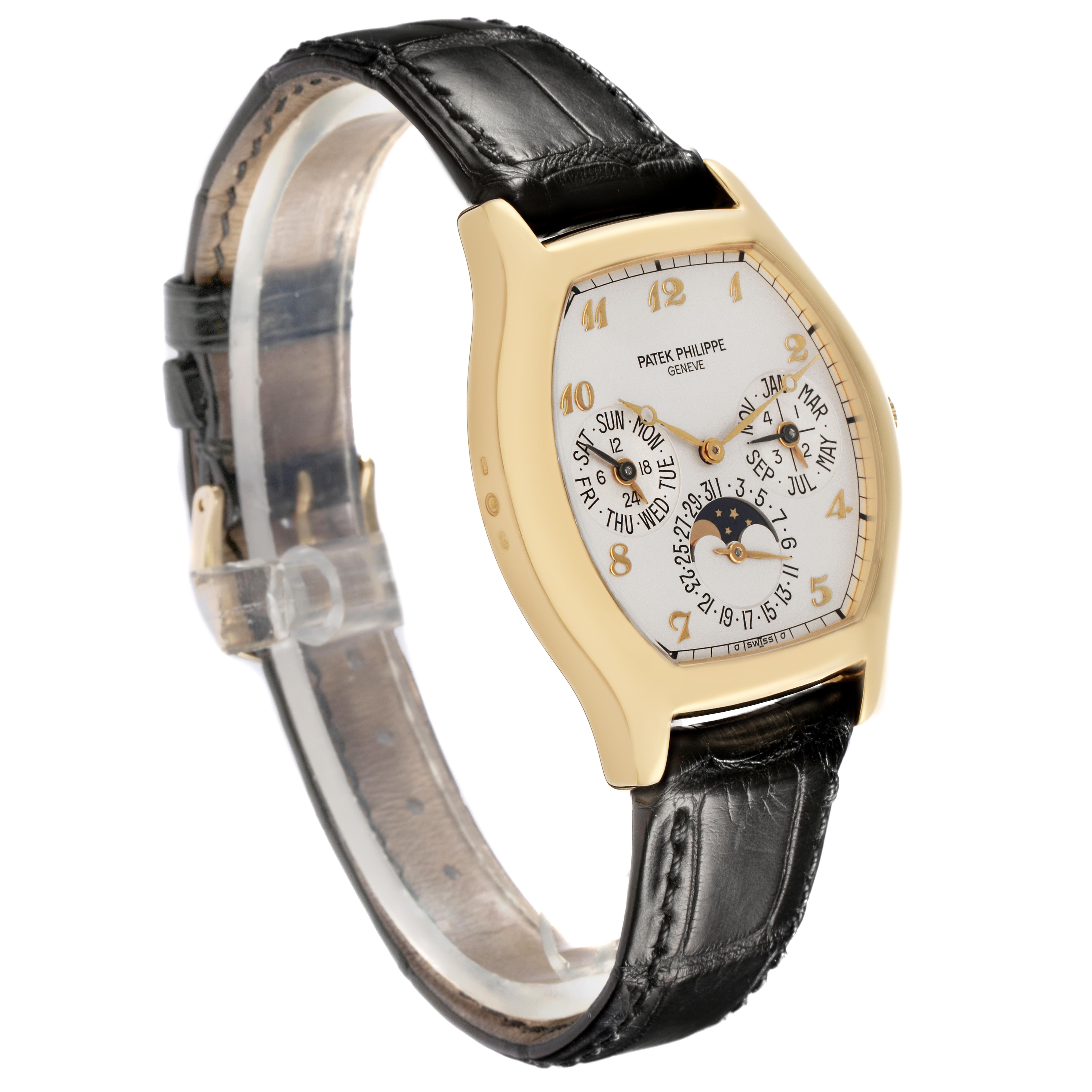 The Patek Philippe Complications 5040J Men
s Yellow Gold Silver Dial 5040J Men
s Yellow Gold Silver Dial watch is shown at a three-quarter angle, displaying its face and black leather strap.