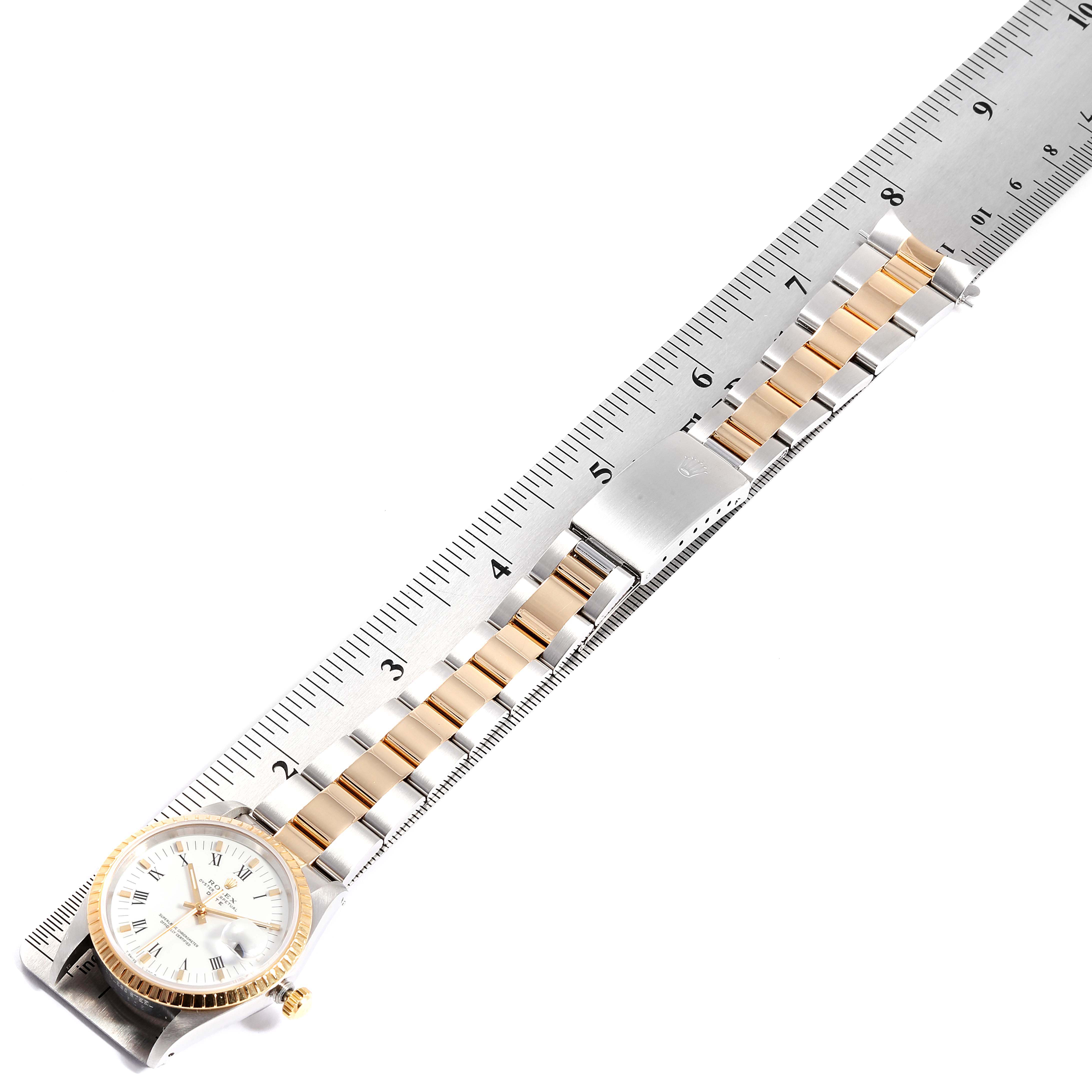This image shows a Date model Rolex watch laid flat alongside a ruler, displaying the dial and bracelet.