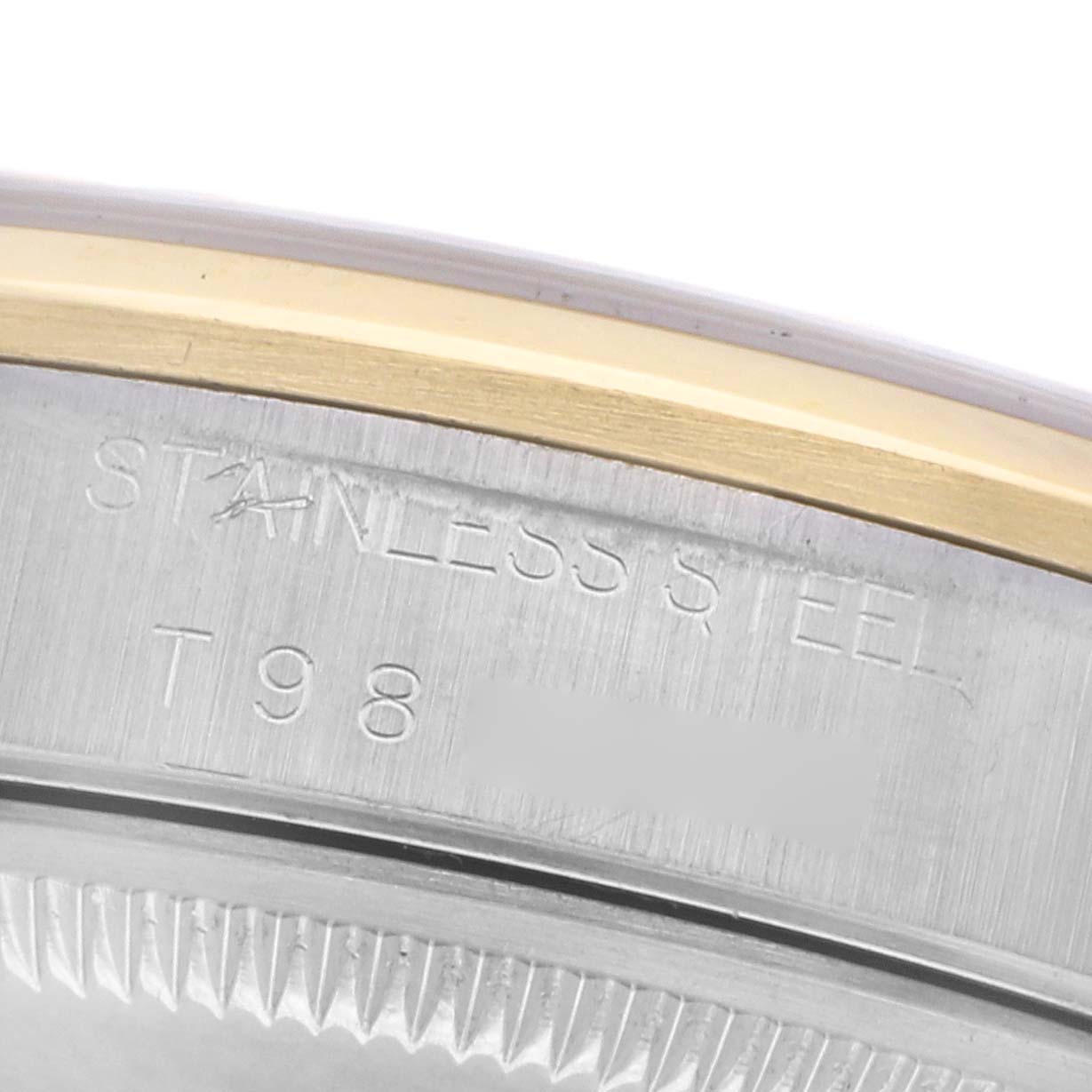 The image shows a close-up of the stainless steel casing edge of a Rolex Date 15203 Men
s Steel and Gold (two tone) Champagne Dial 15203 Men
s Steel and Gold (two tone) Champagne Dial watch, featuring engraved text and part of the bezel.