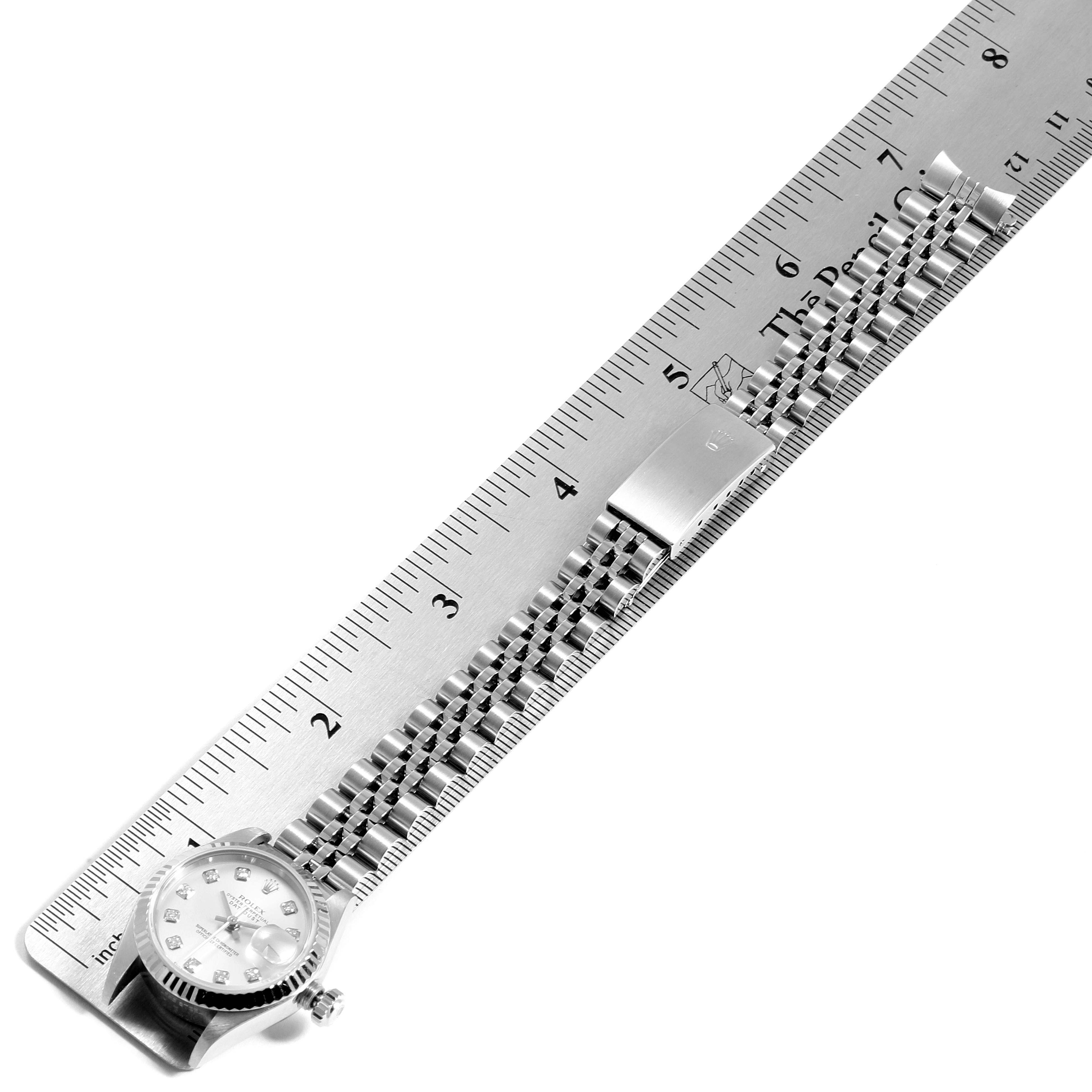 The image shows a flat, overhead view of a Rolex Datejust 79174 Women's Stainless Steel Silver Dial 79174 Women's Stainless Steel Silver Dial watch with a metal bracelet next to a ruler.