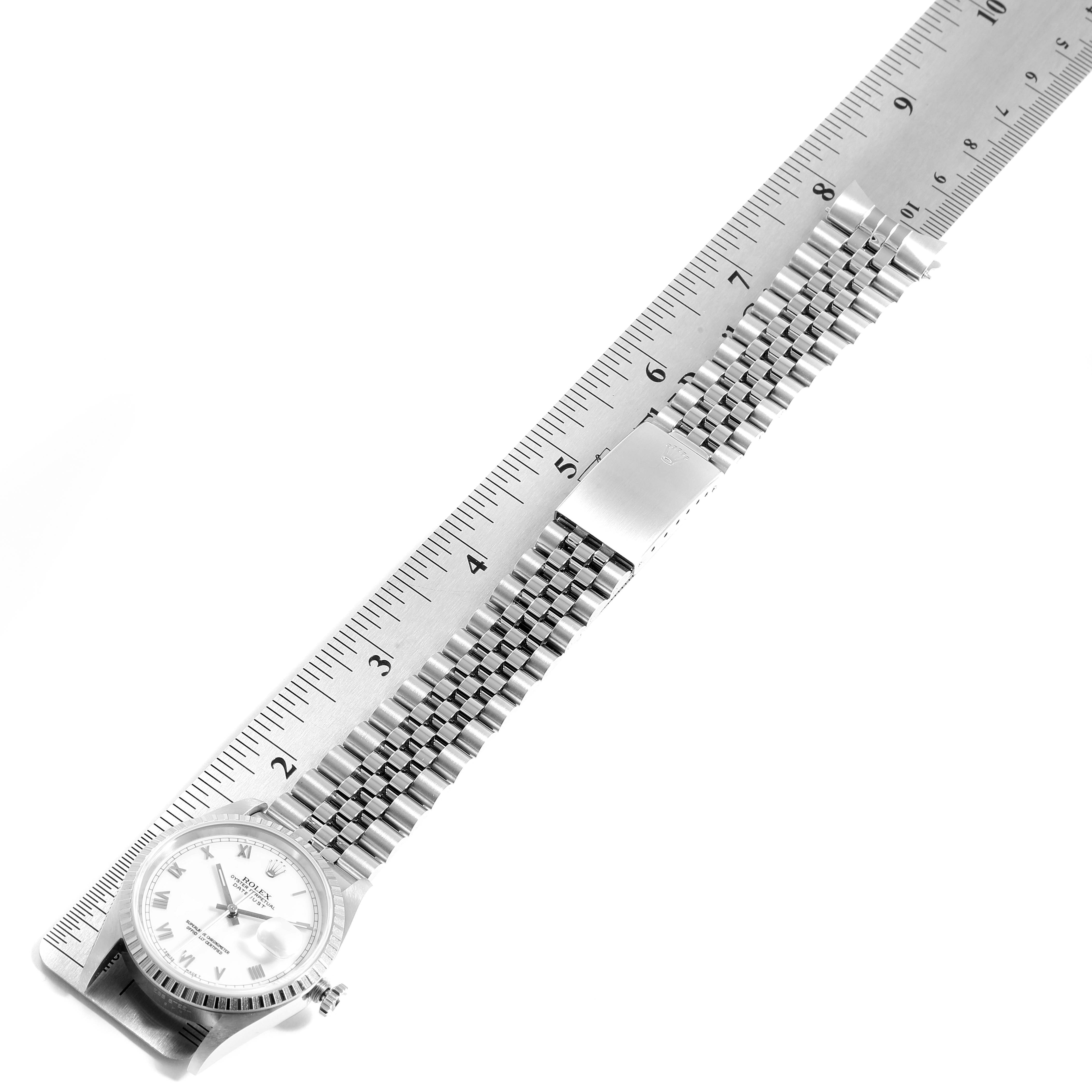 The image shows the Rolex Datejust 16220 Men's Stainless Steel White Dial 16220 Men's Stainless Steel White Dial watch placed diagonally with a metal ruler aligned along its bracelet.