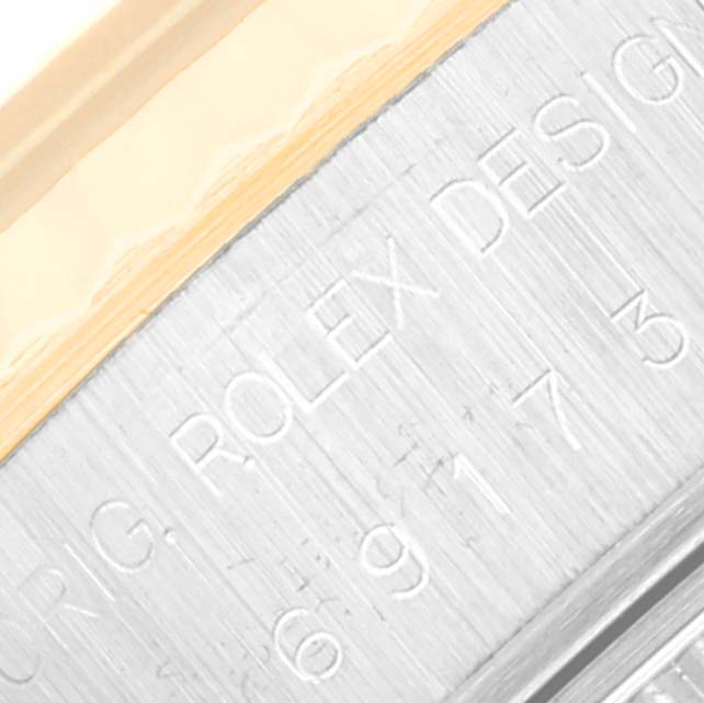 The image shows a close-up of the Rolex Datejust 69173 Women's Steel and Gold (two tone) White Dial 69173 Women's Steel and Gold (two tone) White Dial model's case with engraved text.