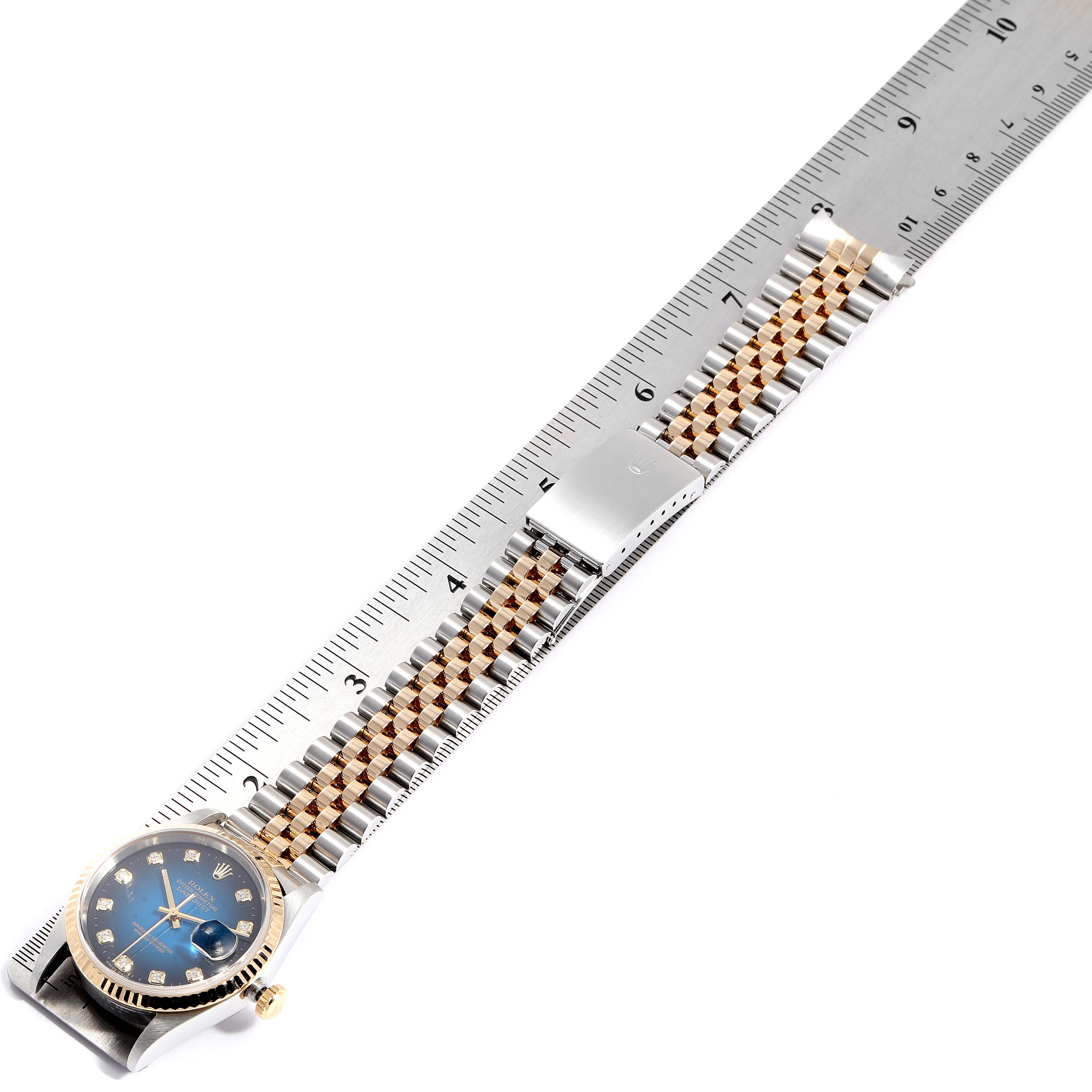 The image shows a Rolex Datejust 16233 Men's Steel and Gold (two tone) Blue Dial 16233 Men's Steel and Gold (two tone) Blue Dial watch laid flat next to a ruler, displaying the dial, bracelet, and clasp.