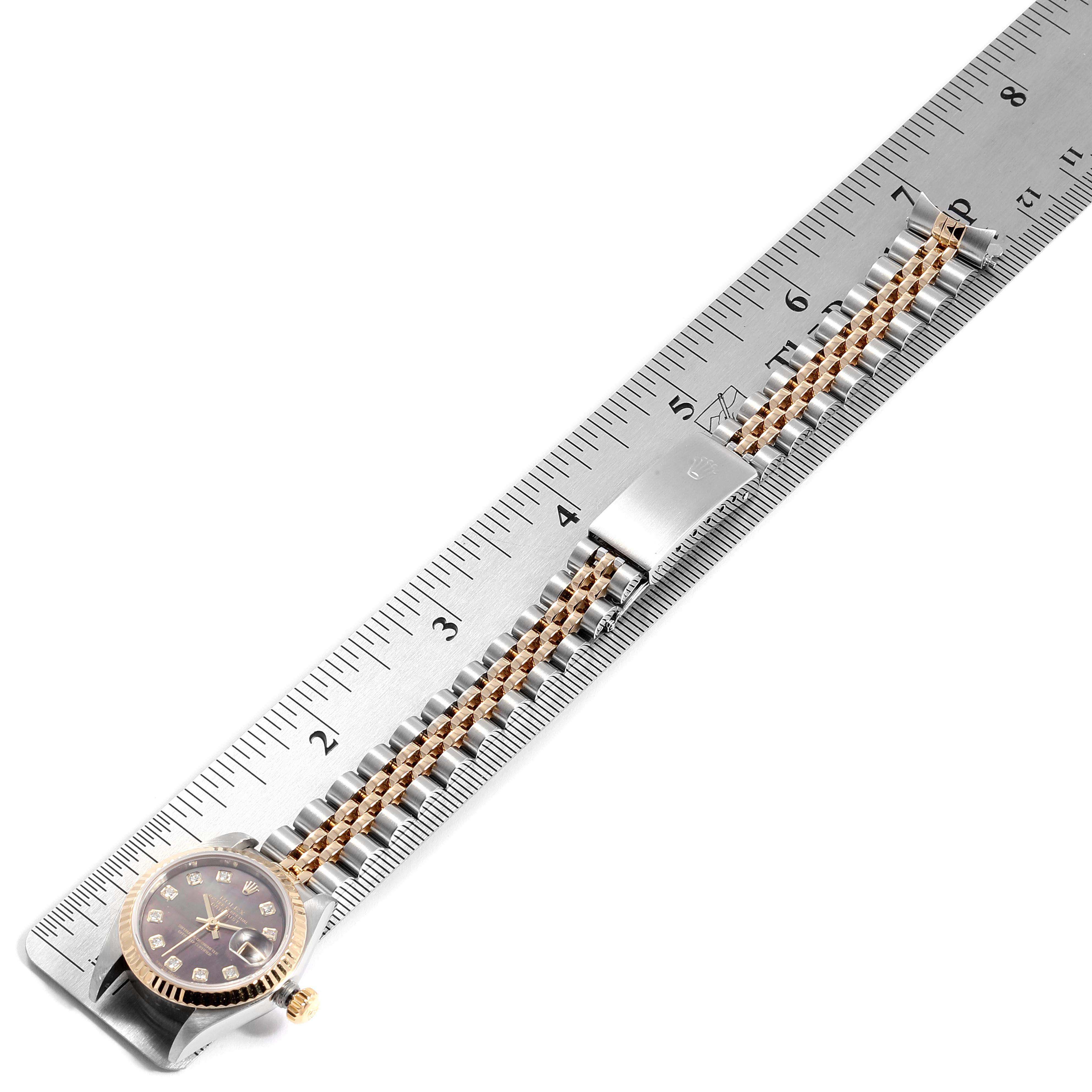 This image shows a Datejust model by Rolex laid out flat against a metal ruler, displaying the watch
s face and full bracelet.