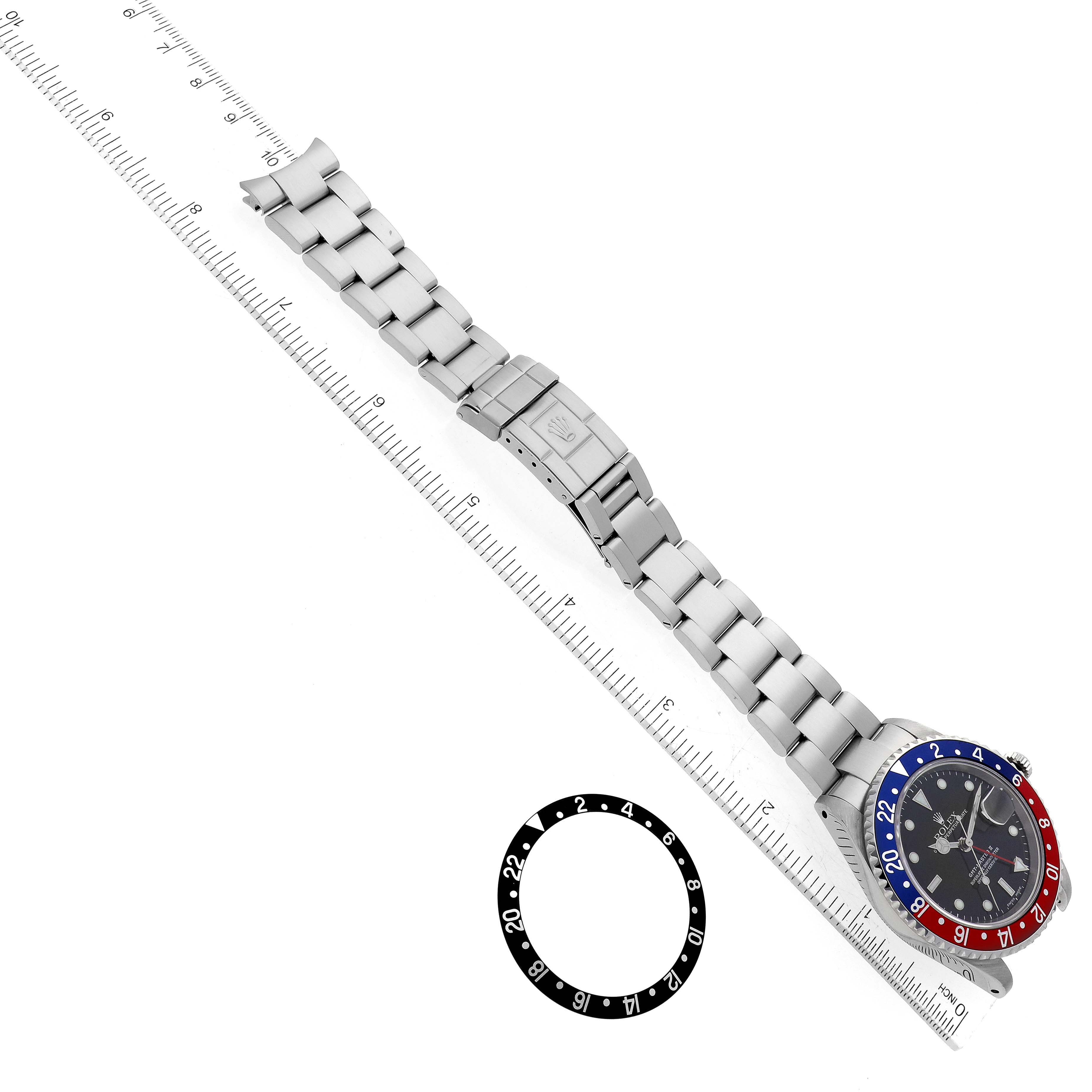 The image shows the Rolex GMT-Master 16710 Men
s Stainless Steel Black Dial 16710 Men
s Stainless Steel Black Dial watch laid flat with the bracelet extended alongside a ruler, and a separate bezel.