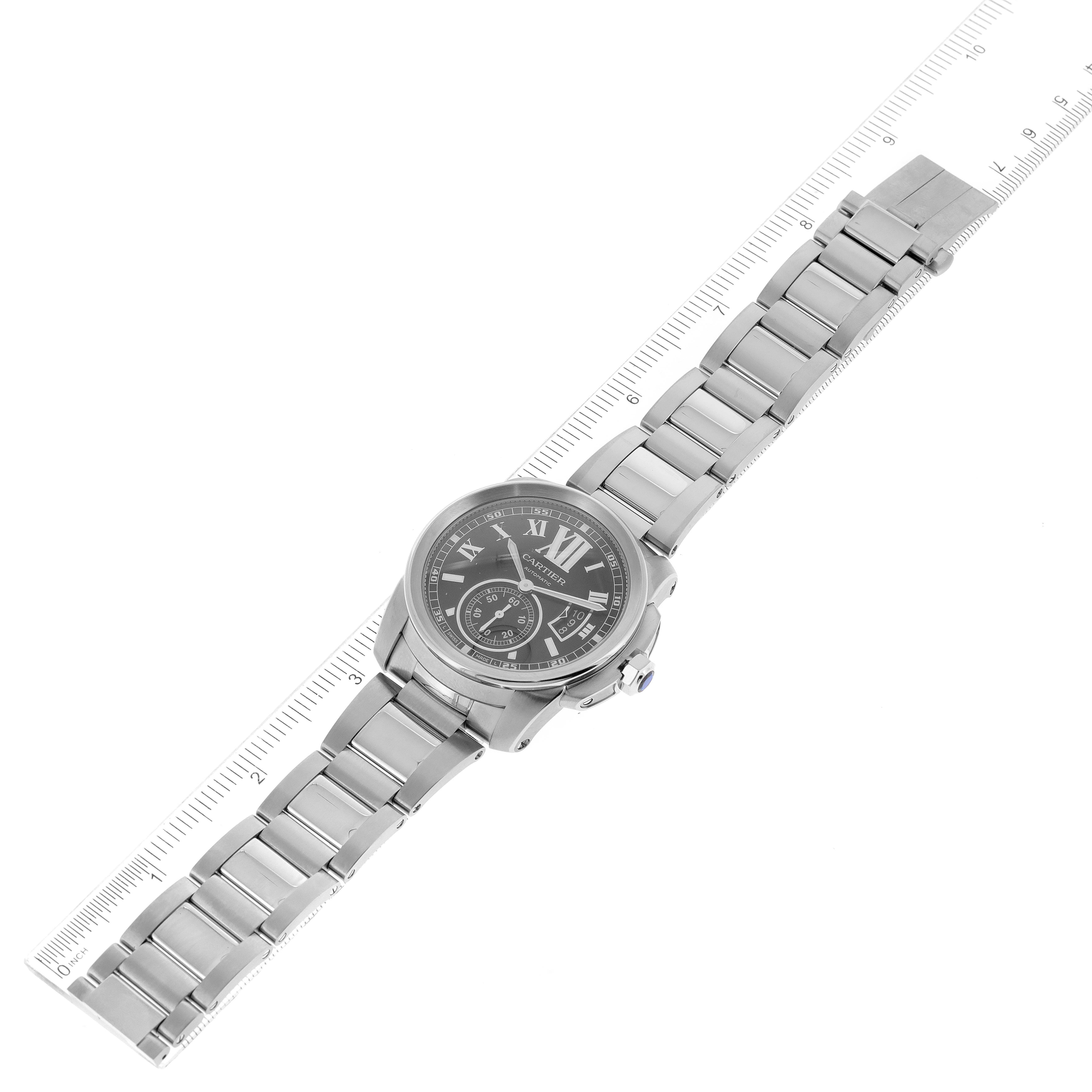 The image shows a top-down view of a Calibre de Cartier model watch by Cartier displaying the watch face and metal bracelet.