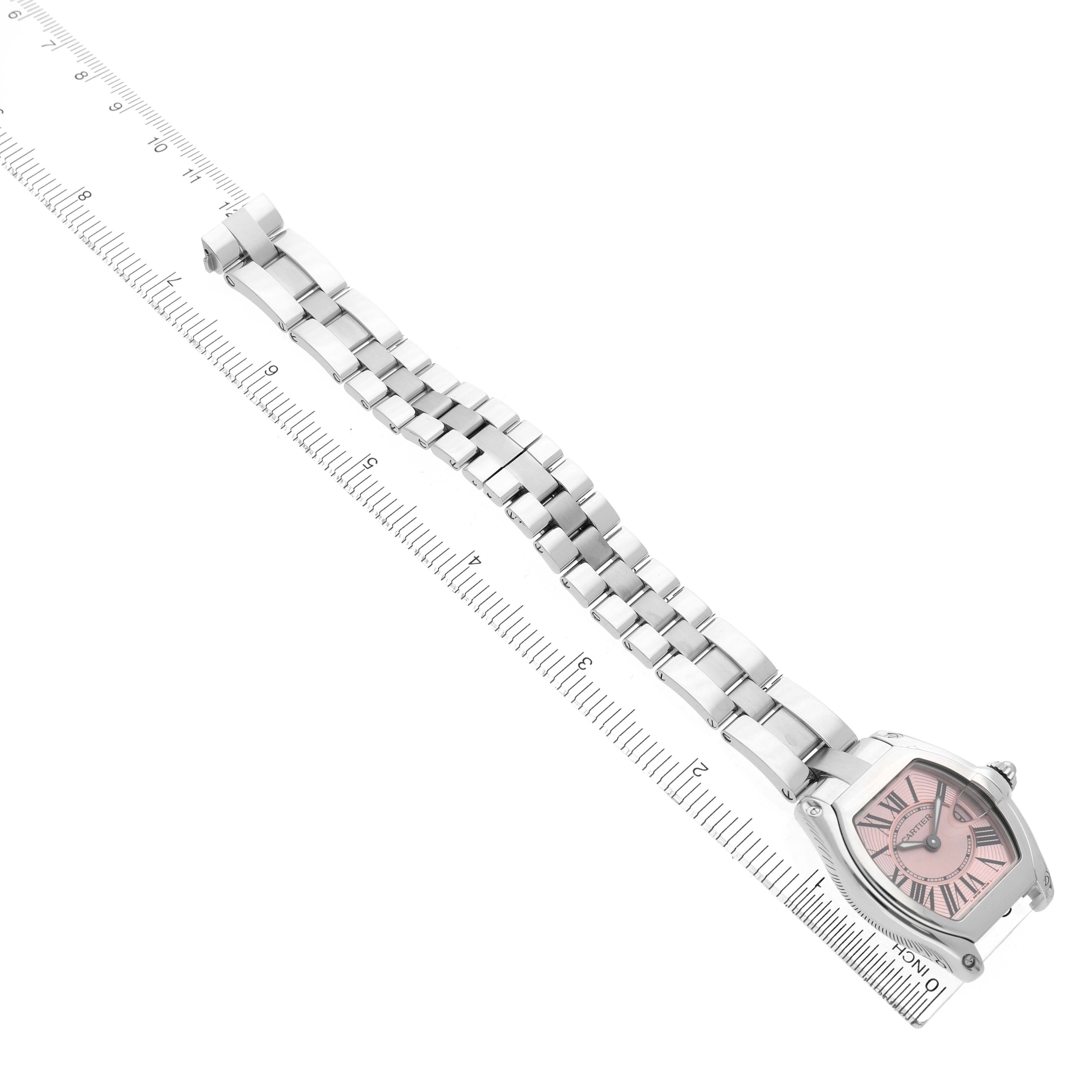 The Cartier Roadster W62017V3 Women's Stainless Steel Pink Dial watch is shown at an angle displaying its pink dial, metal bracelet, and a ruler for scale.