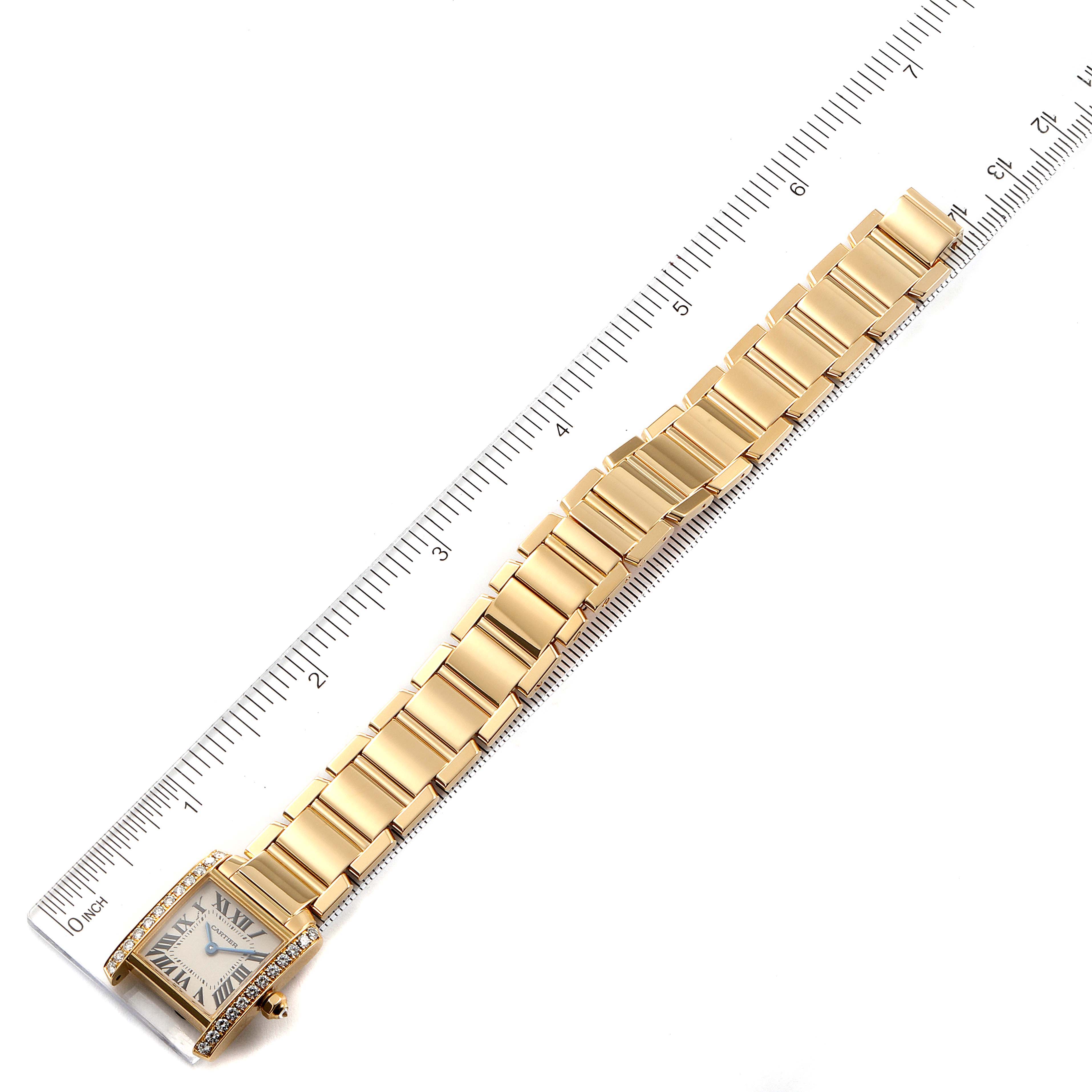 The Cartier Tank Francaise WE1001R8 Women
s Yellow Gold Silver Dial WE1001R8 Women
s Yellow Gold Silver Dial watch is photographed from above, showing the full length of its gold bracelet and rectangular face.
