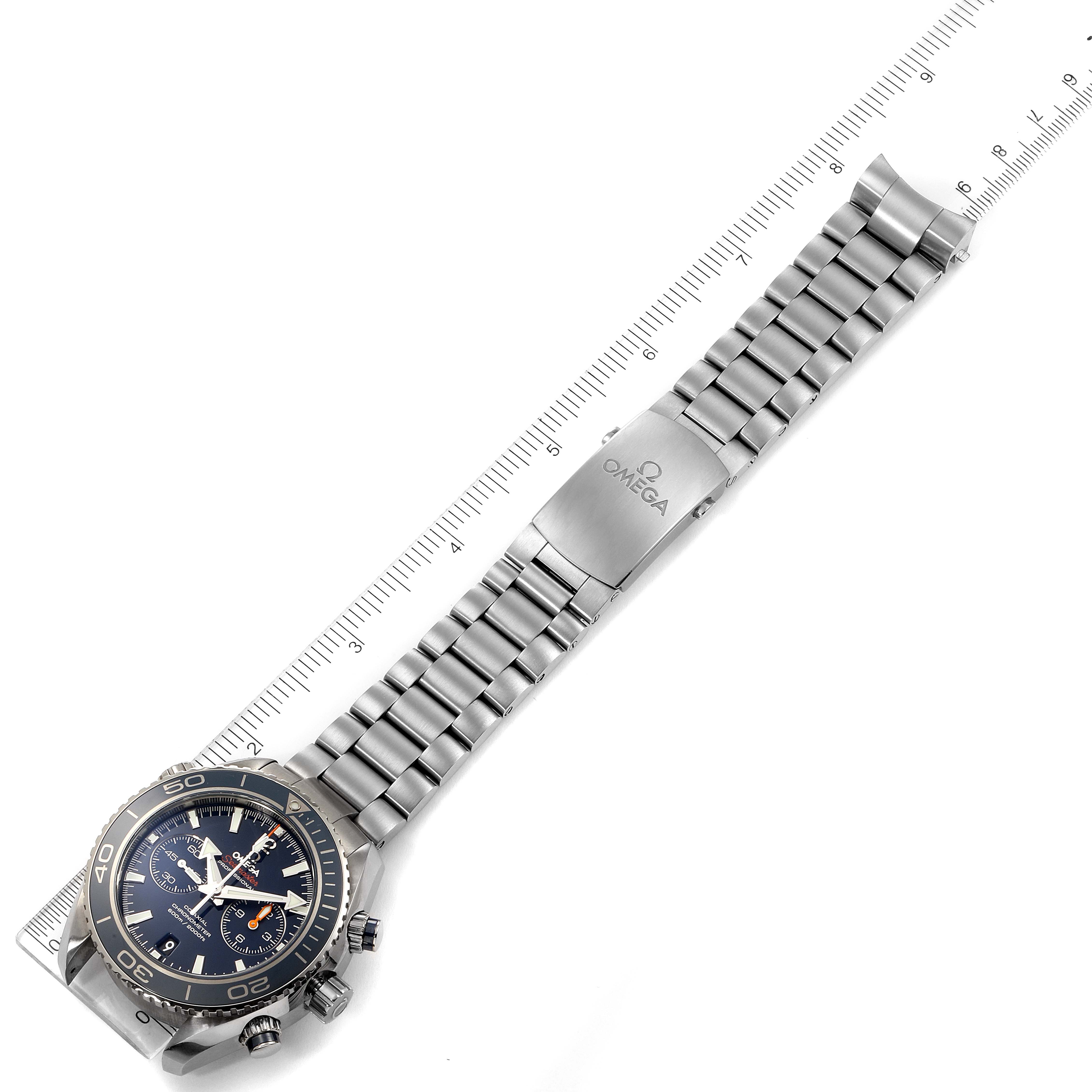 The image shows the Omega Planet Ocean 232.90.46.51.03.001 Men's Titanium Blue Dial 232.90.46.51.03.001 Men's Titanium Blue Dial watch laid flat alongside a ruler, highlighting the face, bezel, and metal bracelet.
